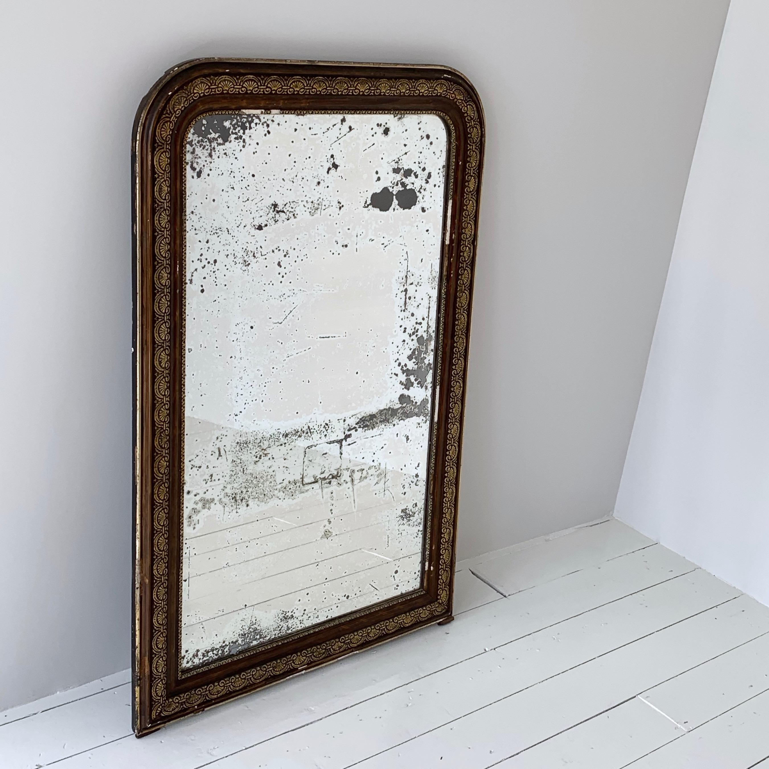 This elegant antique mirror with gold leaf and lacquered finish was crafted in France, circa 1860. The large frame is decorated with hand carved scrolls and foliage and further embellished with decorative edging all around. It is in vintage