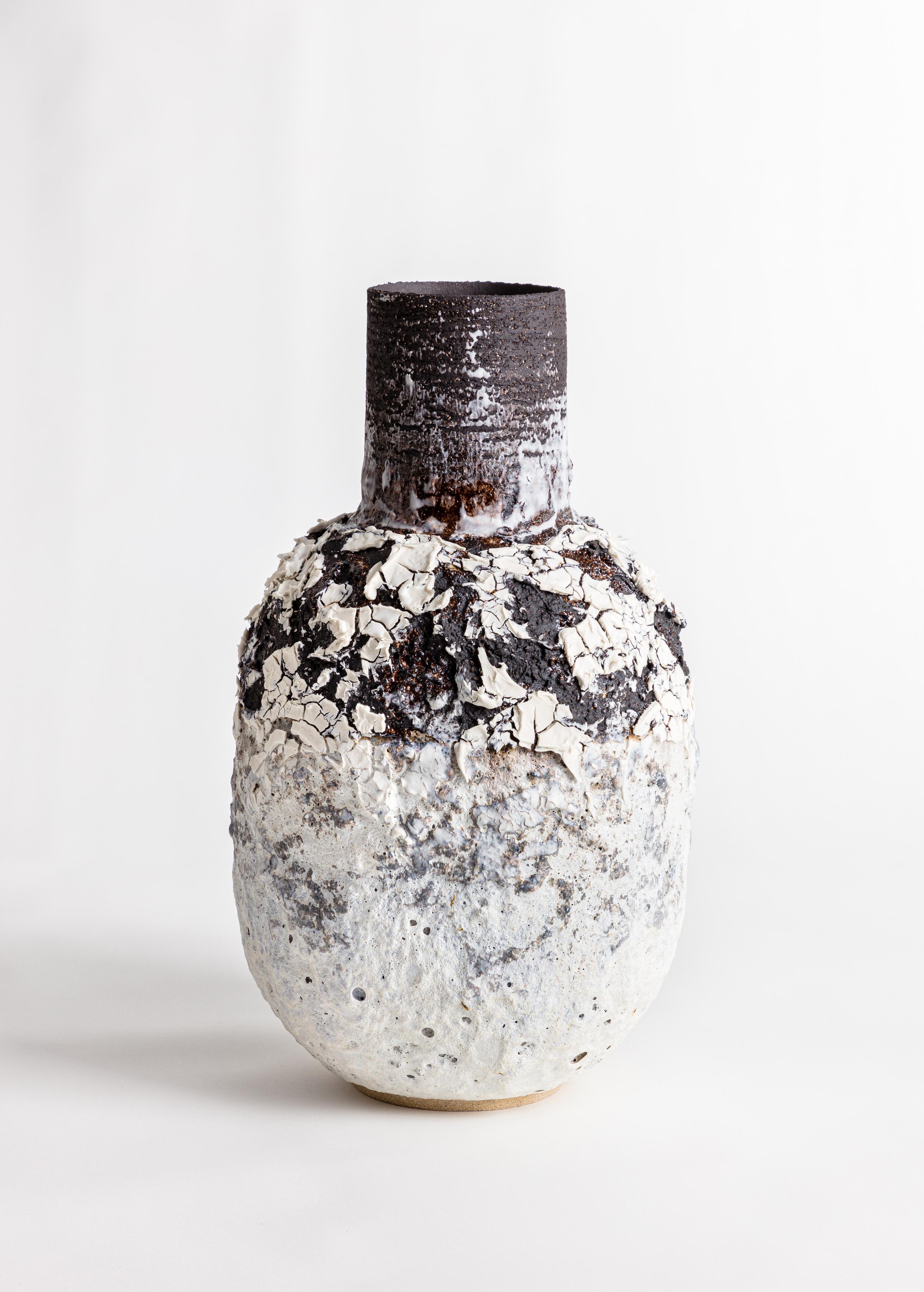 A large heavily textured volcanic bottle shaped vessel with black and white glaze and markings. Made from black textured stoneware clay and porcelain engobe.

Inspiration for the piece comes from the clay itself and the chemical relationships that