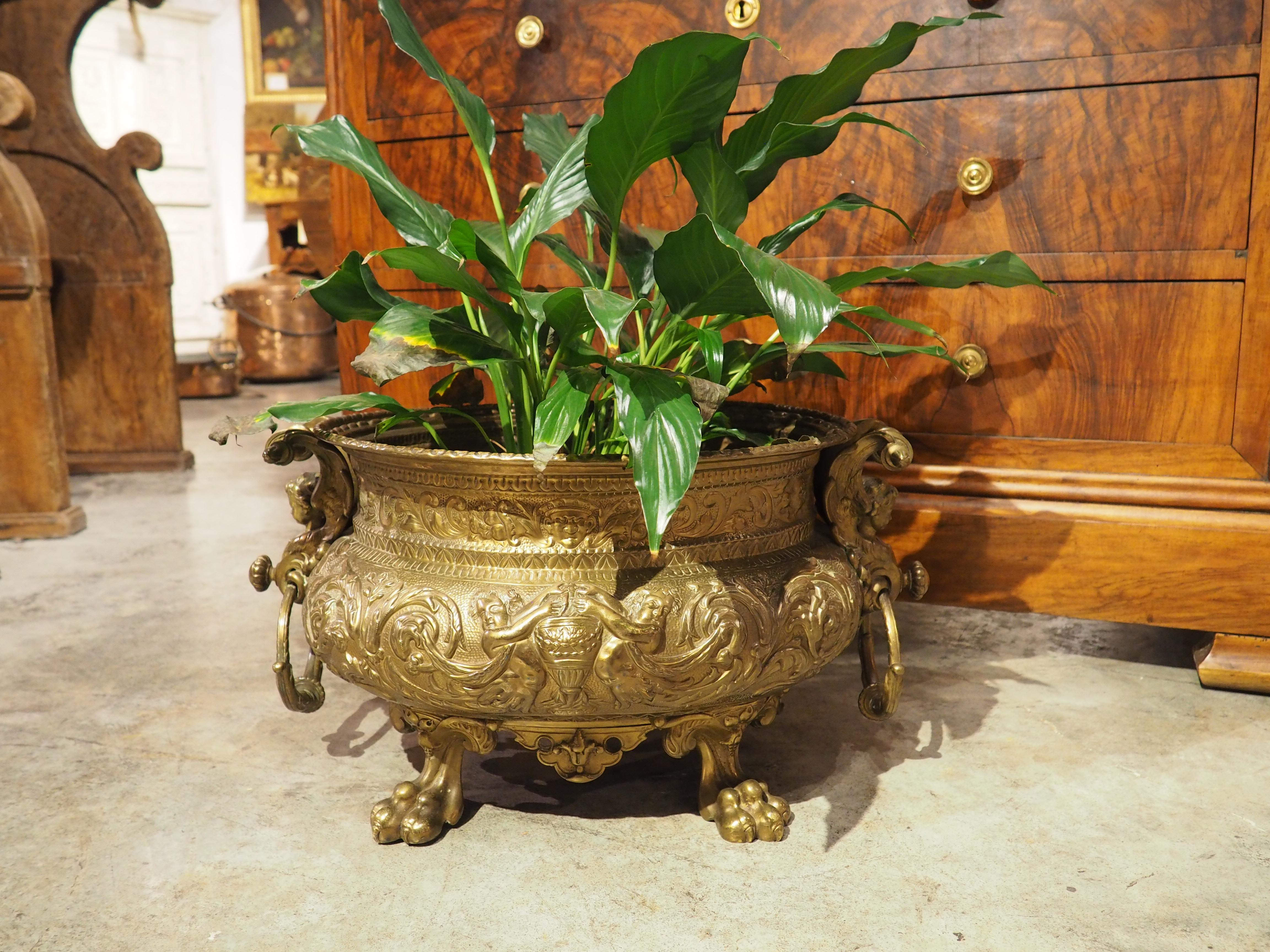 Presque toutes les parties de cette jardinière en laiton français sont ornées d'images vivantes inspirées d'éléments de la nature (comme les pattes) et de la mythologie (génies et chérubins). Cette jardinière très ouvragée a été fabriquée par un