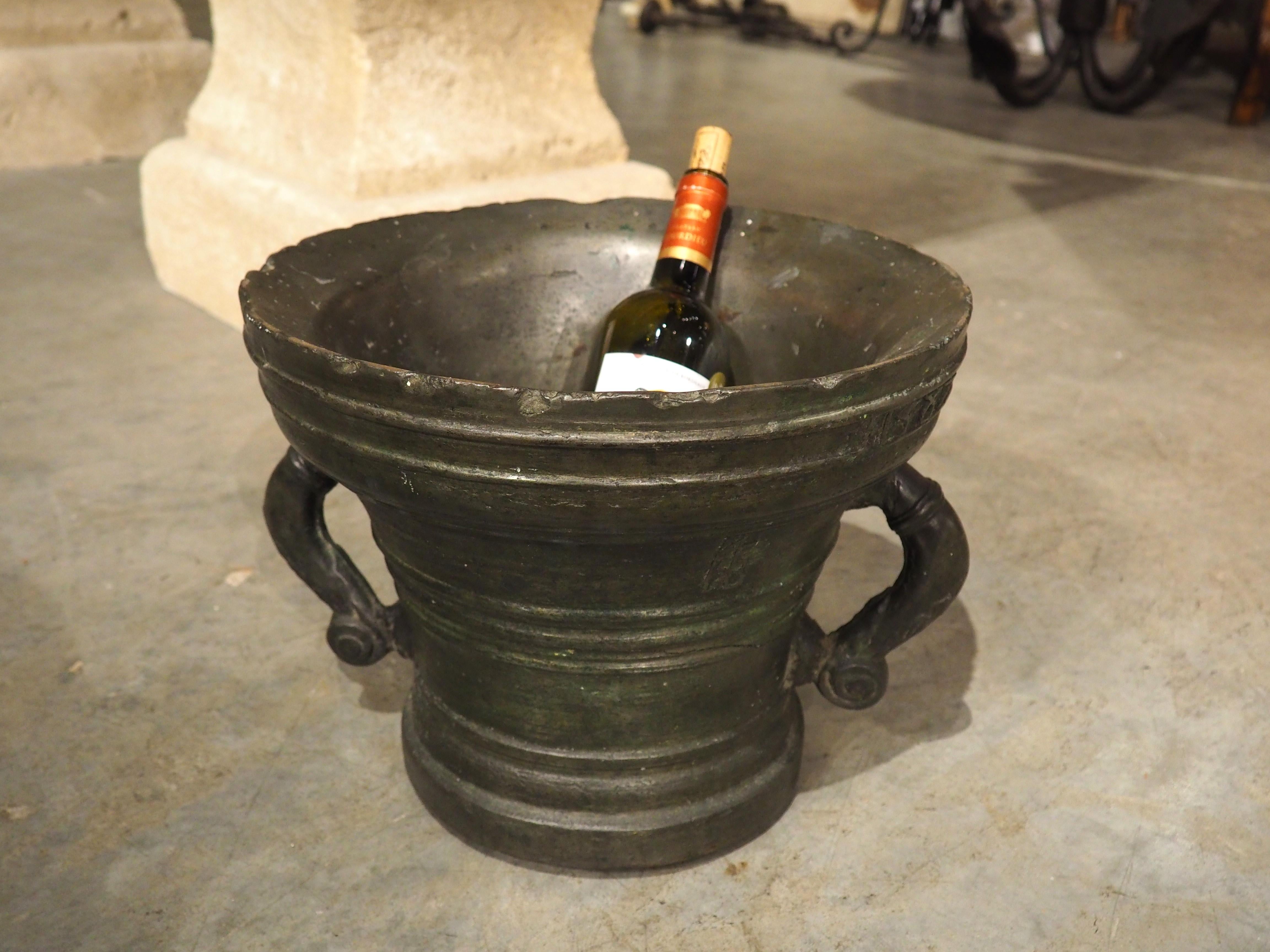 A large and heavy (it weighs 109 lbs!) example of a traditional French pharmacy bowl, this bronze mortar with handles is from 1587, as seen on the production date beneath the molded rim. There is also a maker’s mark on the main body, between two of