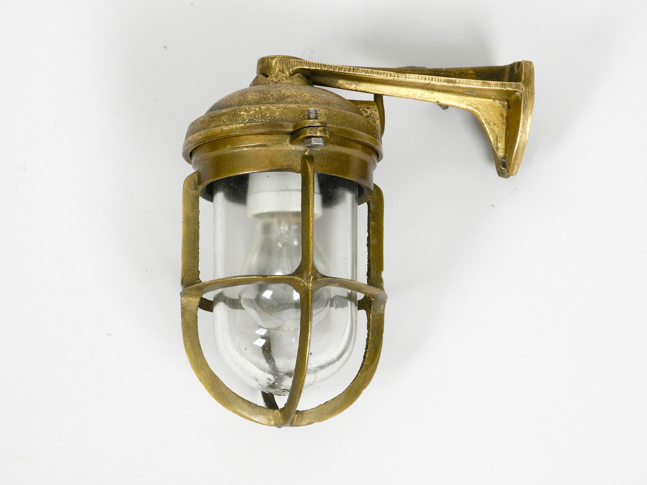 Heavy 1950s ship wall lamp in cast brass.
Beautiful maritime design. With original glass shade. 
No damages to the entire lamp, no cracks or chipping on the glass shade.
100% original condition and fully functional.
Shiny brass. Very nice patina