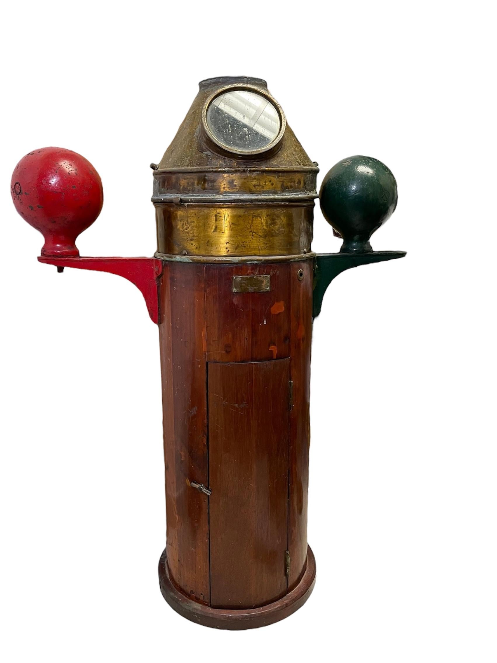 Se trata de una bitácora pesada de barco del siglo XX. Representa una caja/armario cilíndrico de madera con una campana/tapa cónica de latón. Hay una esfera de hierro corrector a cada lado de la parte superior de la caja cilíndrica, una es roja y la