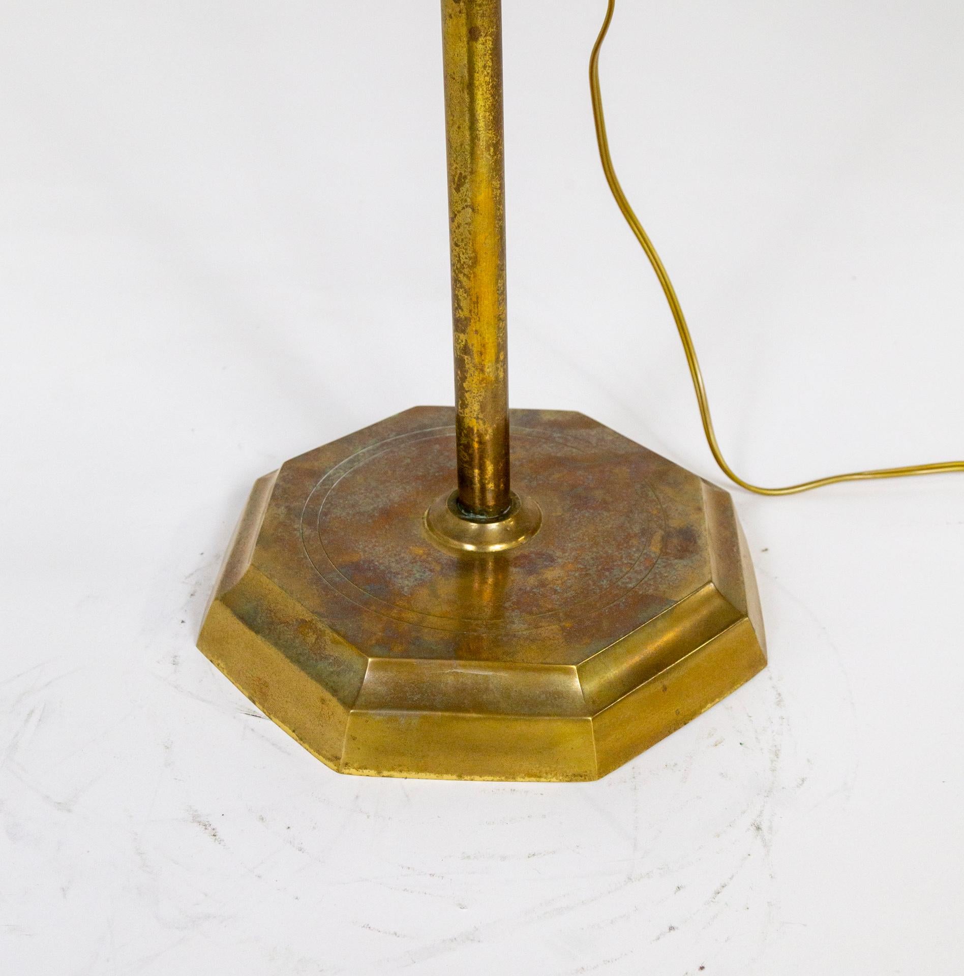 A vintage pharmacy-style floor lamp with adjustable shade and stem height. It is solid brass with a weighted, 8-sided base. The cast brass shade has an enameled white interior and can be adjusted to direct the light. Newly wired with a dimmer on the