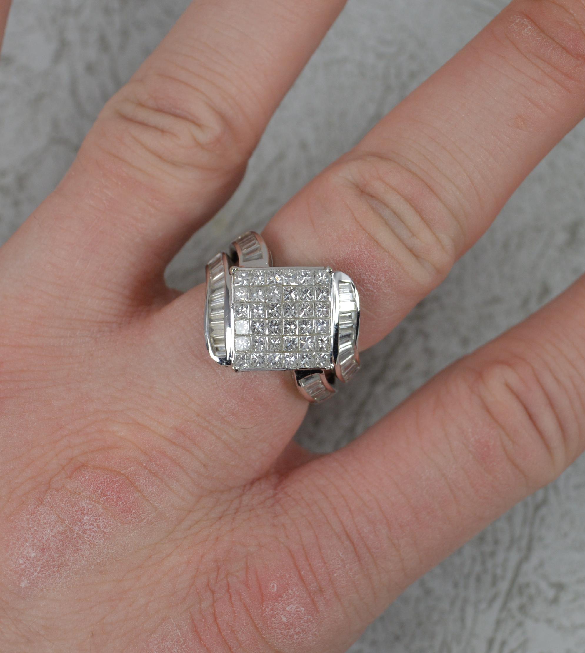 A heavy gold and natural diamond cluster ring.
Solid and chunky 18 carat white gold example.
Designed with a 6x6 grid of princess cut diamonds. Very clean, bright and sparkly. To the shoulders baguette cut diamonds in two rows. 2.03 carats in total