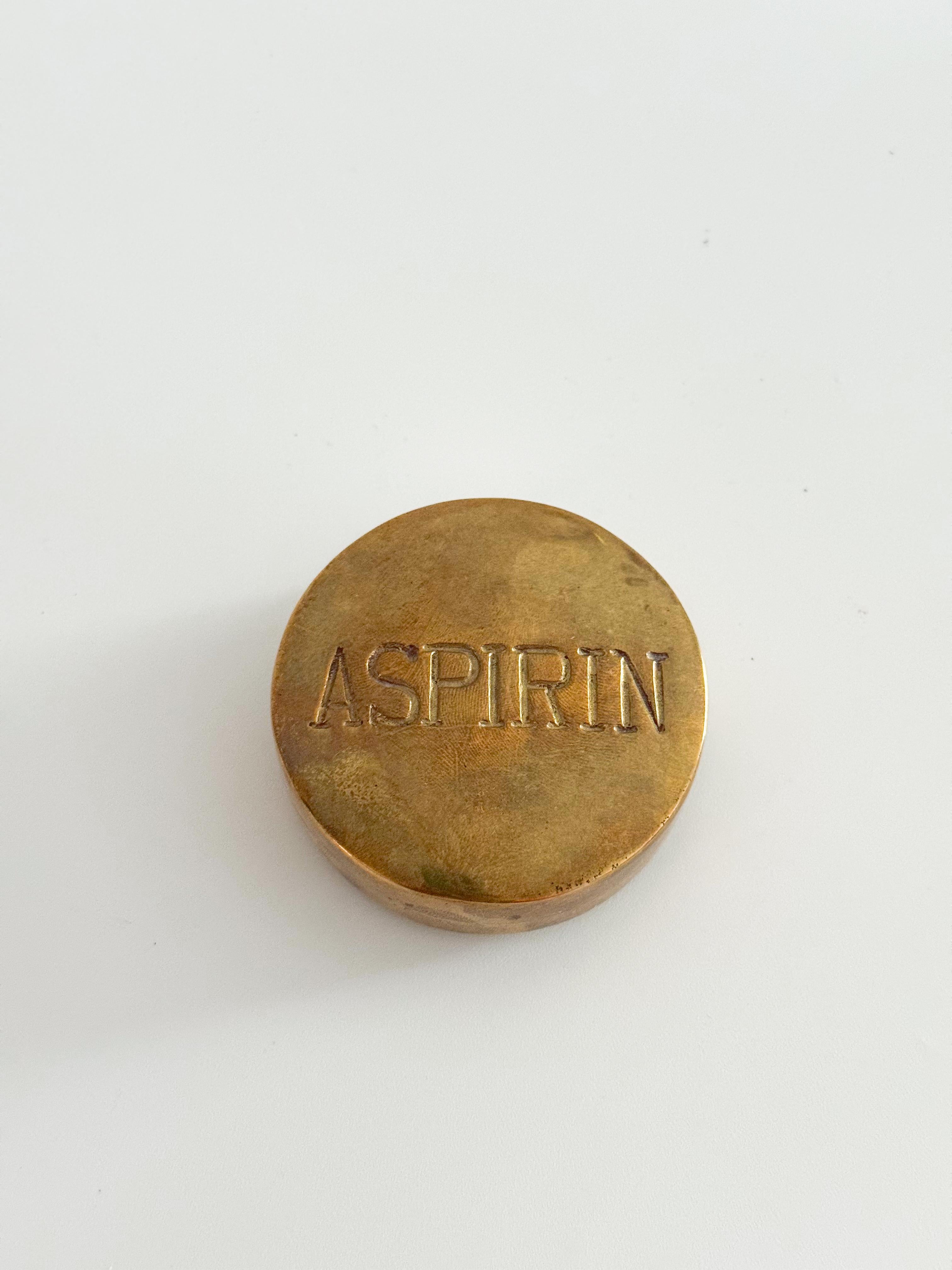This vintage brass aspirin box is a sculptural and functional collectible from the mid-20th century, believed to have been made in the United States between the 1940s and 1960s. Designed with a bold embossed “ASPIRIN” across the top, the piece