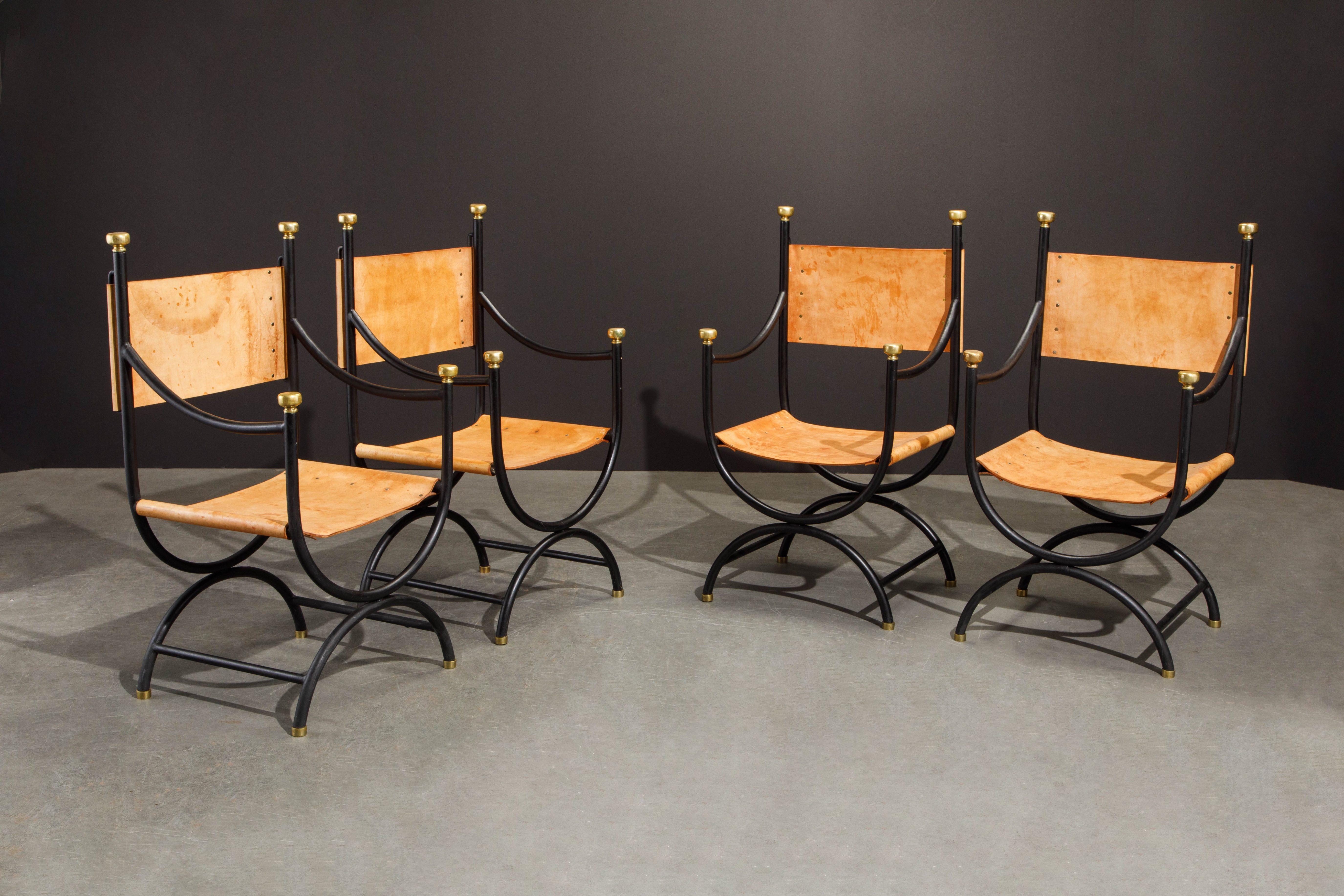 This incredibly high-quality, sizable and hefty set of four (4) modern Savonarola directors chairs features thick natural leather hides with brass rivets, tubular black iron frames finished with very-high-quality heavy brass finials and feet. You