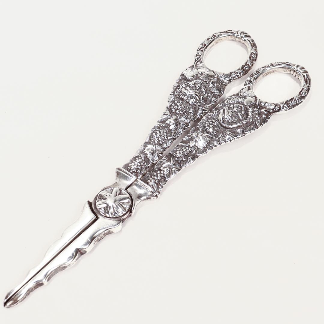 A fine pair of grape shears.

By William Dematteo (or de Matteo).

In cast sterling silver.

With heavy gauge handles with grapes, vines, and comic (or bacchanalian) faces. 

Purchased at Colonial Williamsburg. Retaining the original box and paper