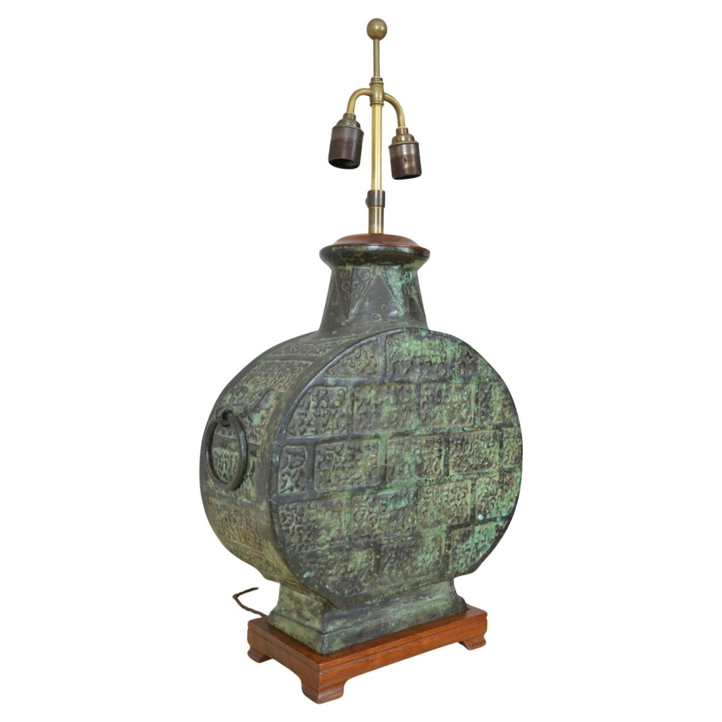 Cette flasque de lune chinoise en bronze massif, très décorative, de style dynastie Han, est magnifiquement patinée en un vert vert profond. Les côtés aplatis sont ornés de masques de taotie appliqués tenant des poignées en anneau, et s'élèvent à