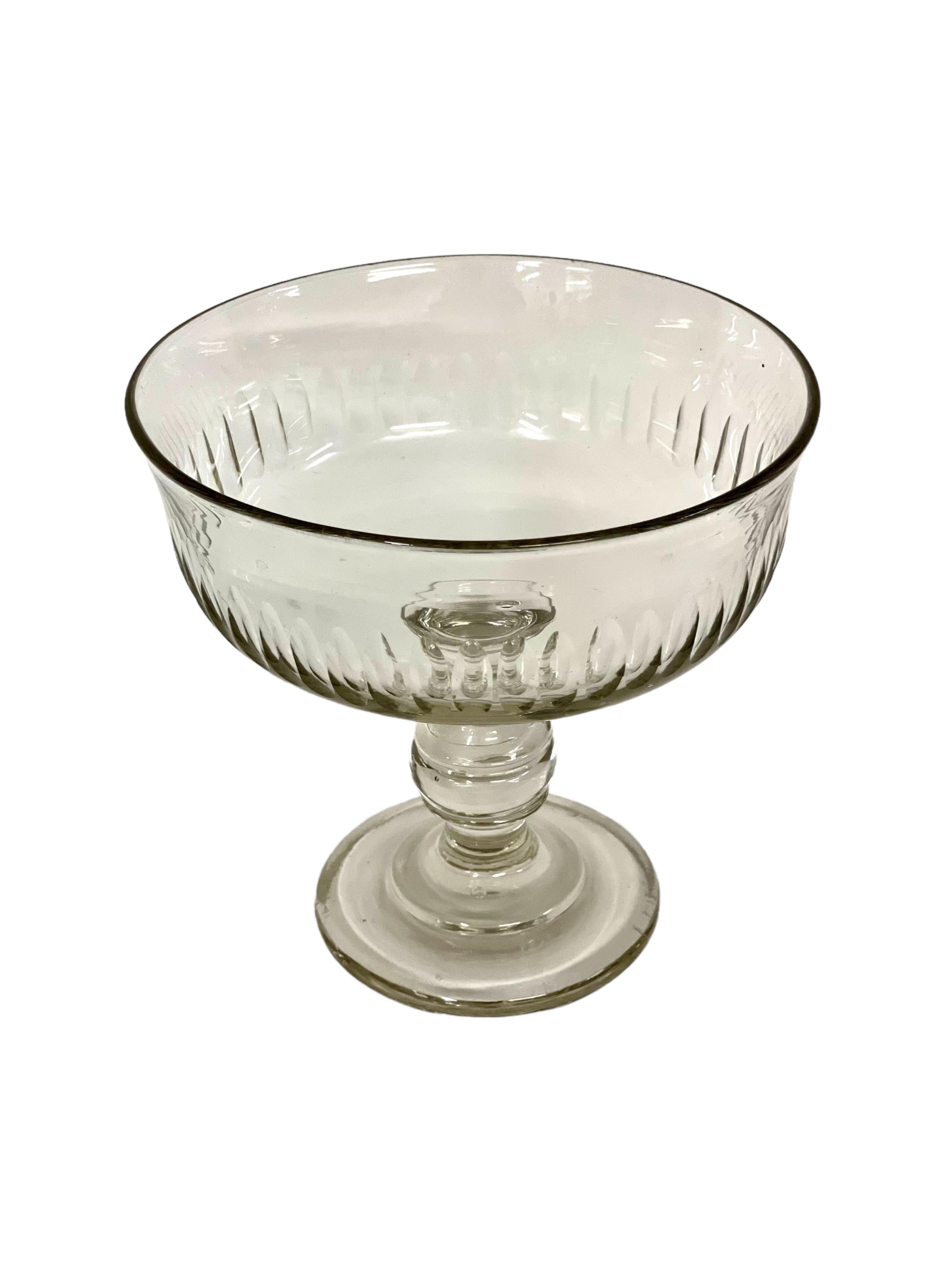 Questa elegante ciotola con piedistallo in cristallo tagliato, o coupe, risale al XX secolo. Realizzato in cristallo pesante di alta qualità, presenta lati profondi che sono stati tagliati con un lungo disegno ellittico nella metà inferiore, che