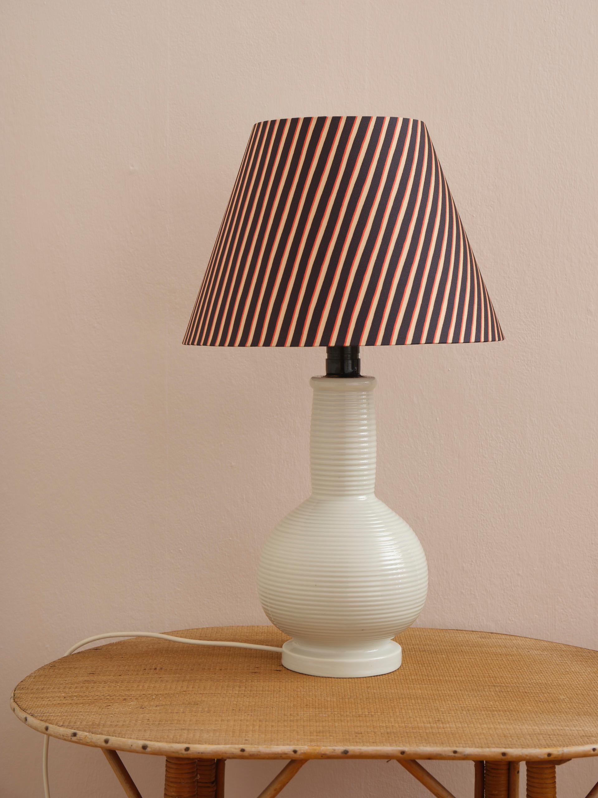 Lampe de table minimaliste et imposante du Mid-Century en lourde porcelaine blanche rayée. Fabriqué au Danemark et en très bon état. La lampe est vendue sans l'abat-jour (ici présenté avec un abat-jour en tissu Painted Stripe de la designer textile