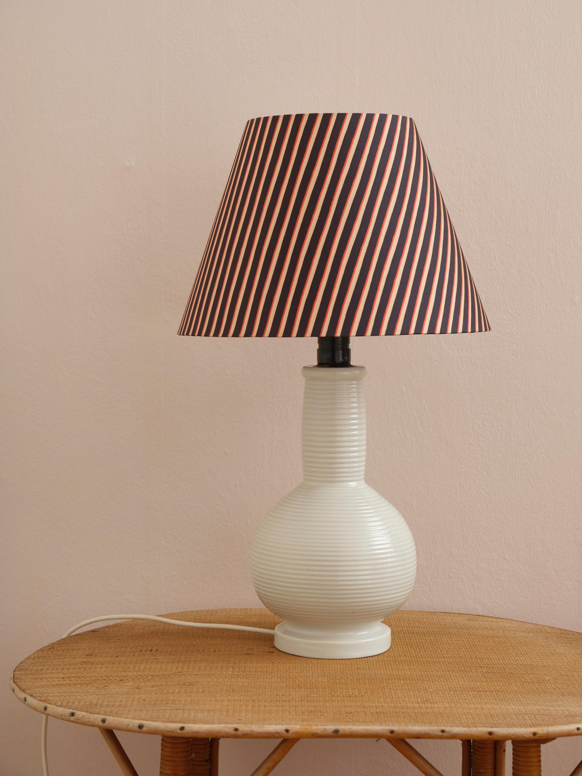 Minimalist and imposant Mid-Century table lamp in heavy white rifled porcelain. Made in Denmark and in great condition. The lamp is sold without the shade in the fabric Painted Stripe by Danish textile designer Helene Blanche.
Height: 37 cm (14.6