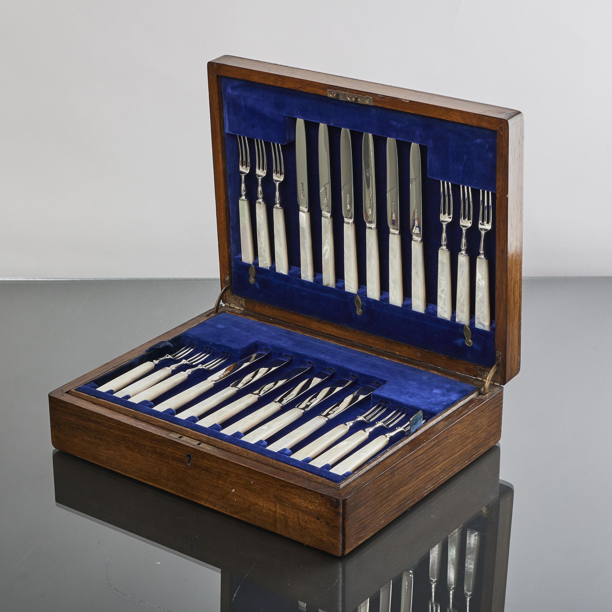 24 fruit or hors d'oeuvres knives and forks in their original wooden case. While the handles are mother-of-pearl, the blades and prongs are solid silver. A charming set of knives and forks in excellent condition.
