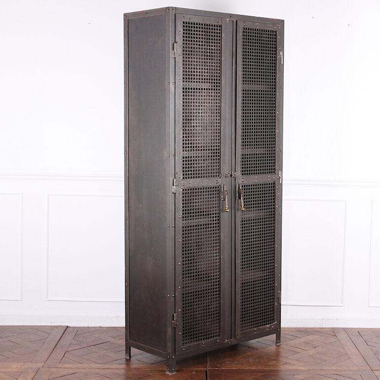 Unusual heavy (about 350lbs) steel cabinet with pierced mesh doors which open to four fixed welded shelves. The corners and doors of the cabinet are reinforced with riveted thick gauge steel plate. Handsome turned drop-pull handles; simple latches