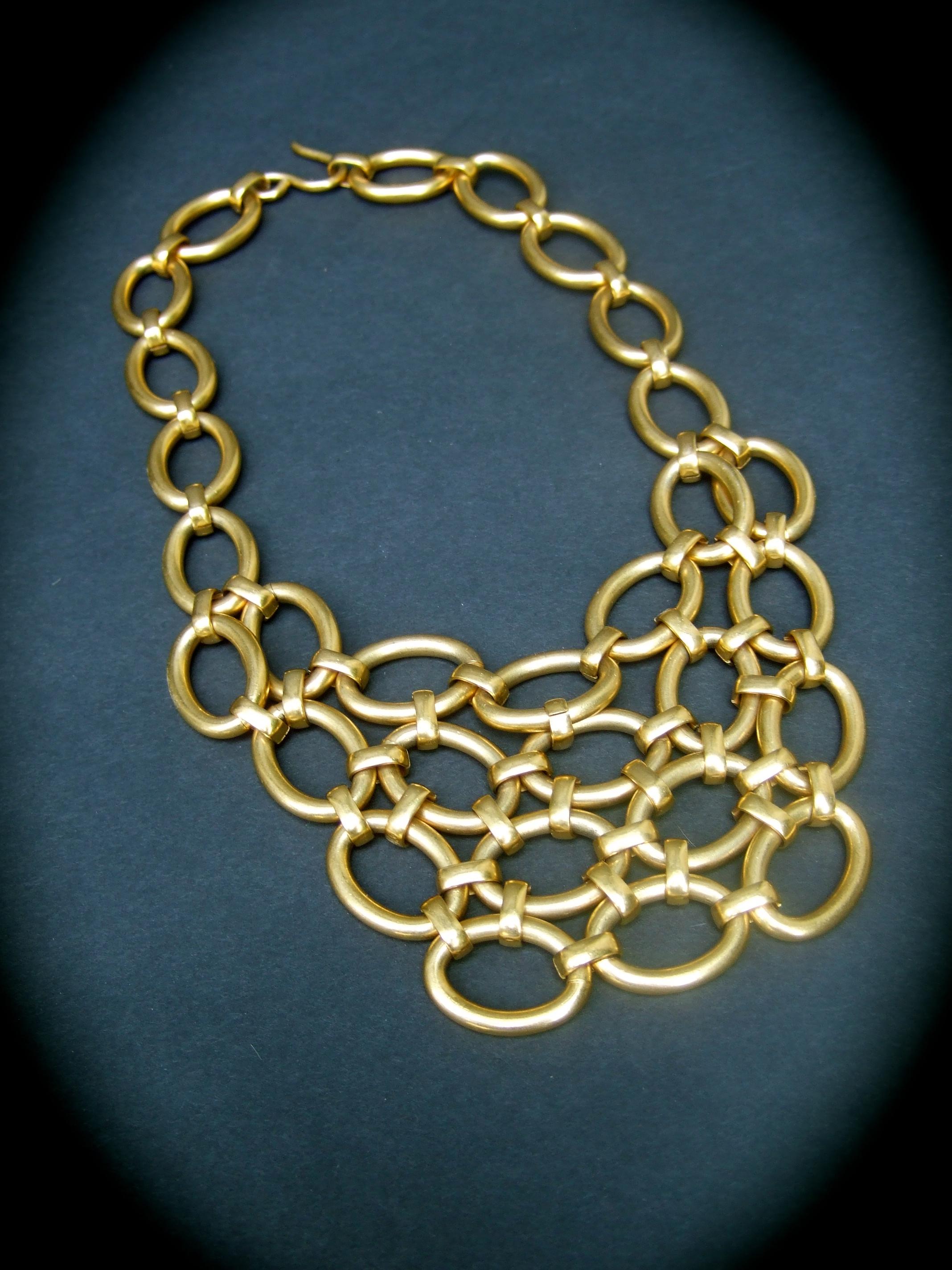 Heavy gilt matte metal articulated statement necklace c 1990s
The chic necklace is designed with a collection of oval elongated 
hinged articulated rings sheathed in luminous matte tone metal 

The series of rings collectively is substantial in