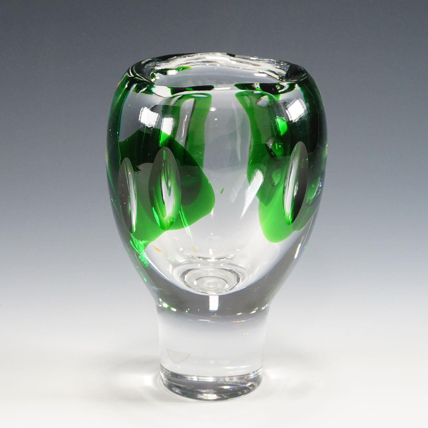 A heavy art glass vase designed by Vicke Lindstrand for Kosta Sweden ca. 1960ties. The thick clear glass has green glass applications and polished olive cuttings on the body. It is marked with manufacturer lable and incised signature (kosta 46690