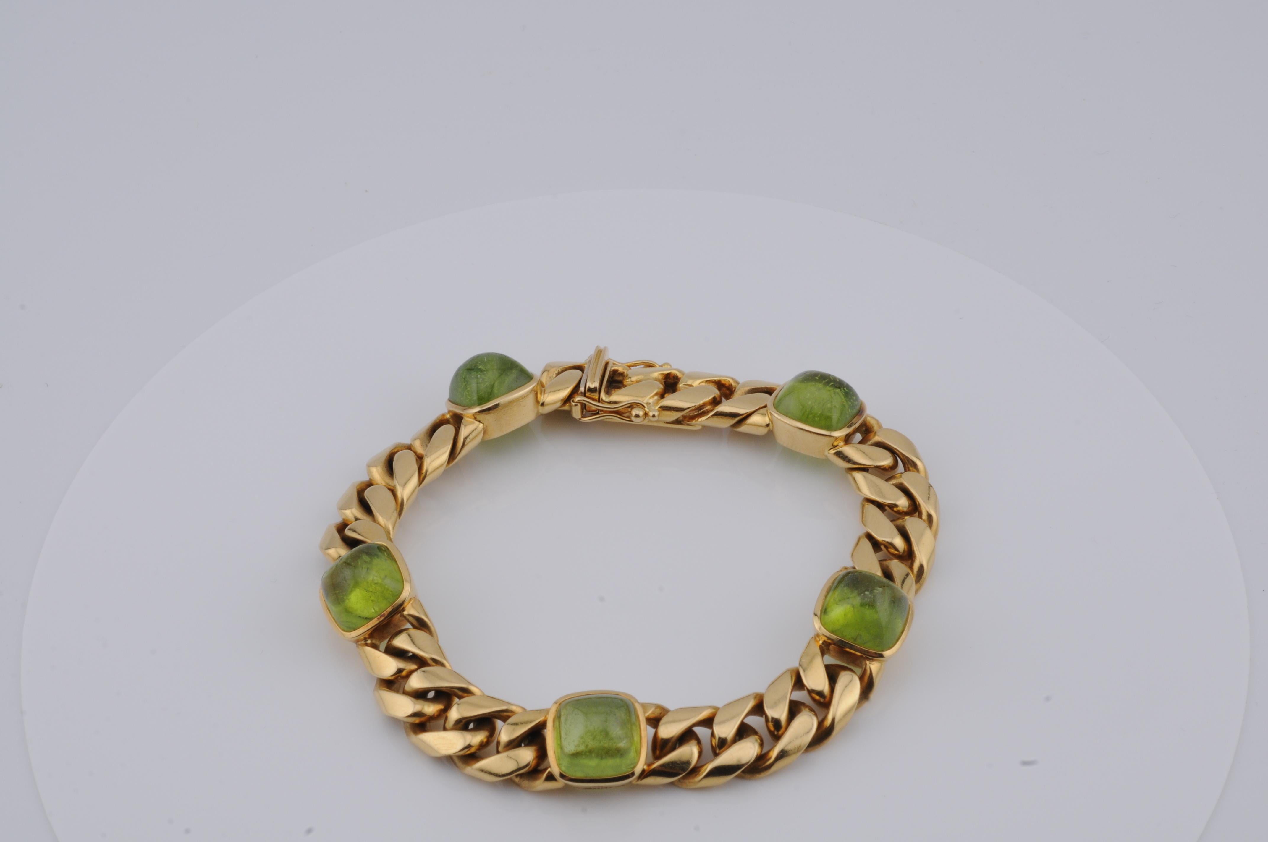 Solid curb bracelet in 18k yellow gold, weighing approximately 72g. Set with five peridot cabochons, each around 2ct, totaling approximately 10ct. The vibrant green stones are elegantly integrated into the design, adding color and distinction.