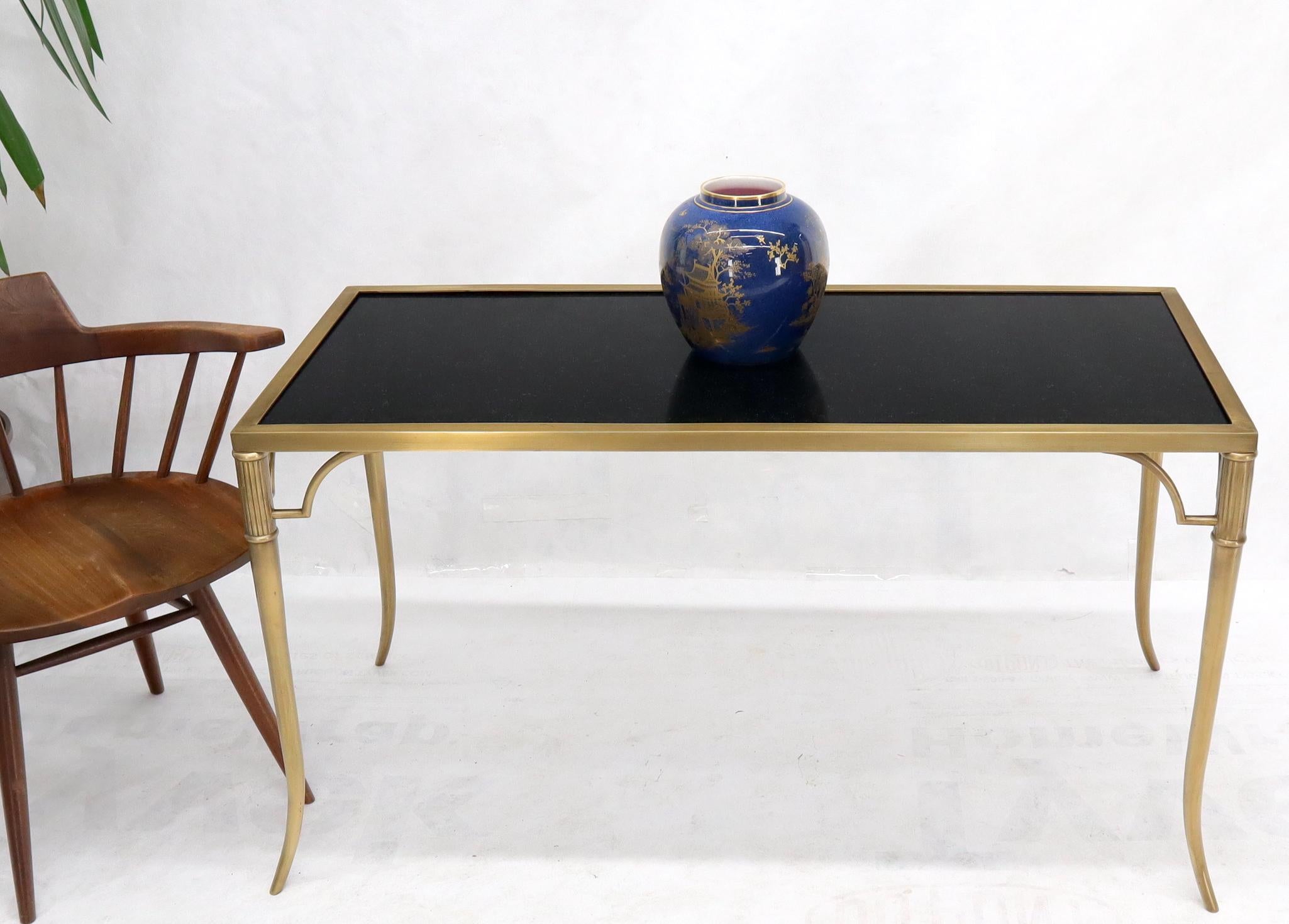Table basse en matériaux lourds, composée d'un plateau en granit noir massif et d'un cadre en laiton massif avec des pieds effilés.