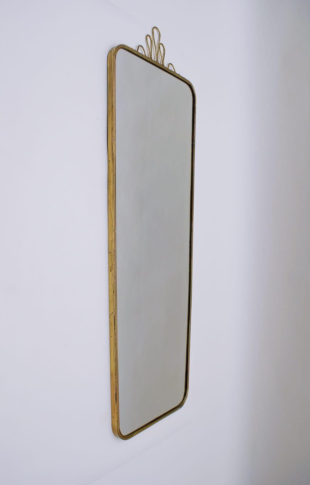 Exceptional rare midcentury brass wall mirror. Made in Italy.
Great 1950s Minimalist design. Very high quality and elegantly production.
Above is a brass crown.
Heavy and very solidly built.
Total height with crown 117cm, mirror height