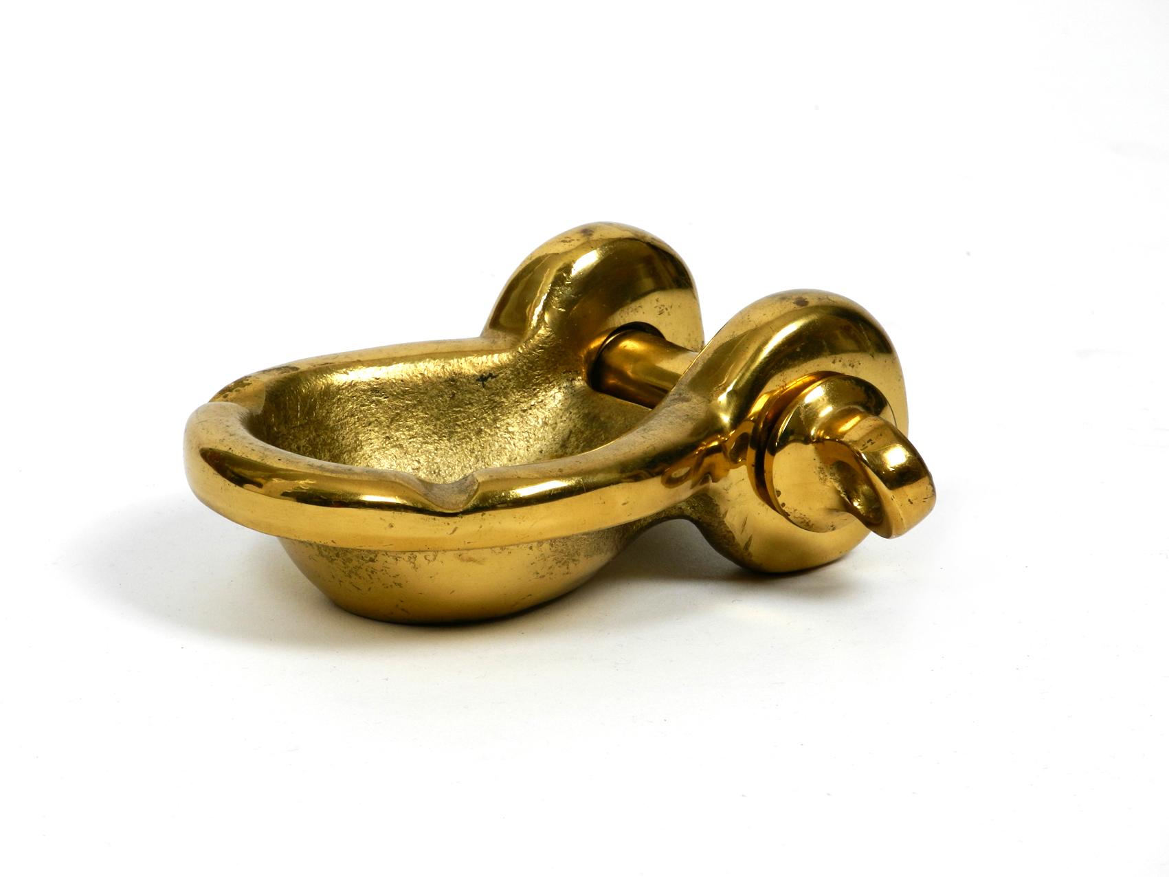 Rare heavy midcentury ashtray in the shape of a ship's shackle. Made of solid brass with a great patina and very decorative.
Screw cap can be turned out.

Measures: Length x width: 14 x 10 cm / 5.5
