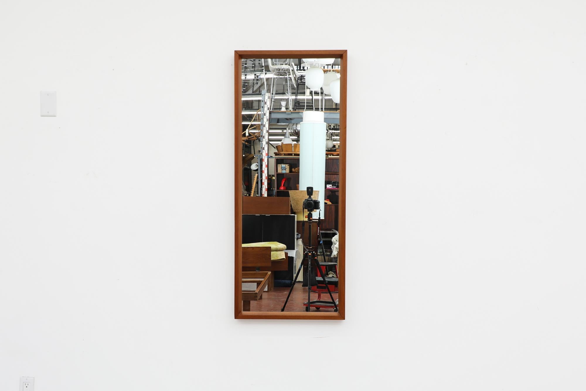 Heavy Mid-Century tall wall mount mirror with teak frame. In good original condition with visible patina. Wear is consistent with its age and use.