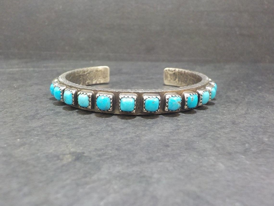 This tufa cast beauty is sterling silver with 21 genuine turquoise gemstones.

Measurements: 5/8 of an inch wide. Inner circumference of 6 1/4 inches including the 1 inch gap
Weight: 38.7 grams

Marks: None