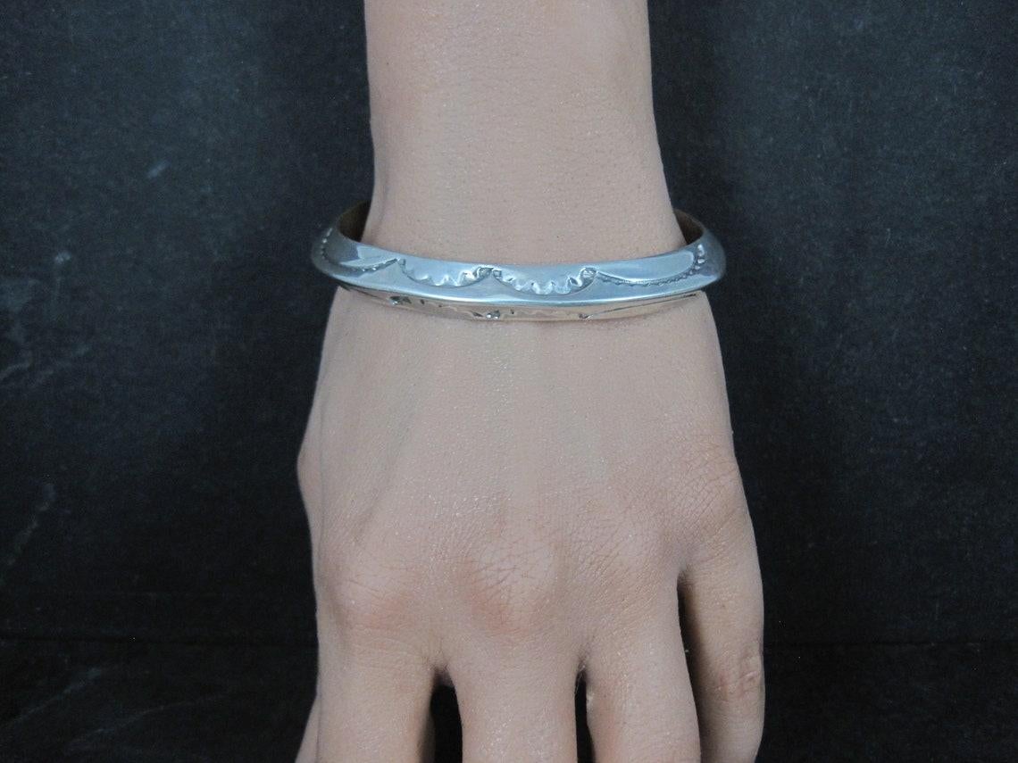 This gorgeous carinated cuff bracelet is sterling silver.
It is a creation of the Navajo silversmith family, the Tahes.

The face of this cuff tapers from 9mm to 12mm.
It has an inner circumference of 6 1/2 inches including the 1 inch gap.
Weight: