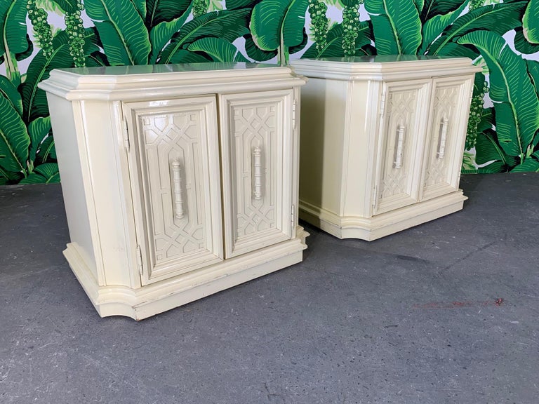 Pair of nightstands featuring chinoiserie style detailing. Double doors open to reveal ample storage. High gloss lacquer finish in ecru. Made by National Mt. Airy but unmarked. Good condition, with scuffs and abrasions to finish (see photos).
 
 
