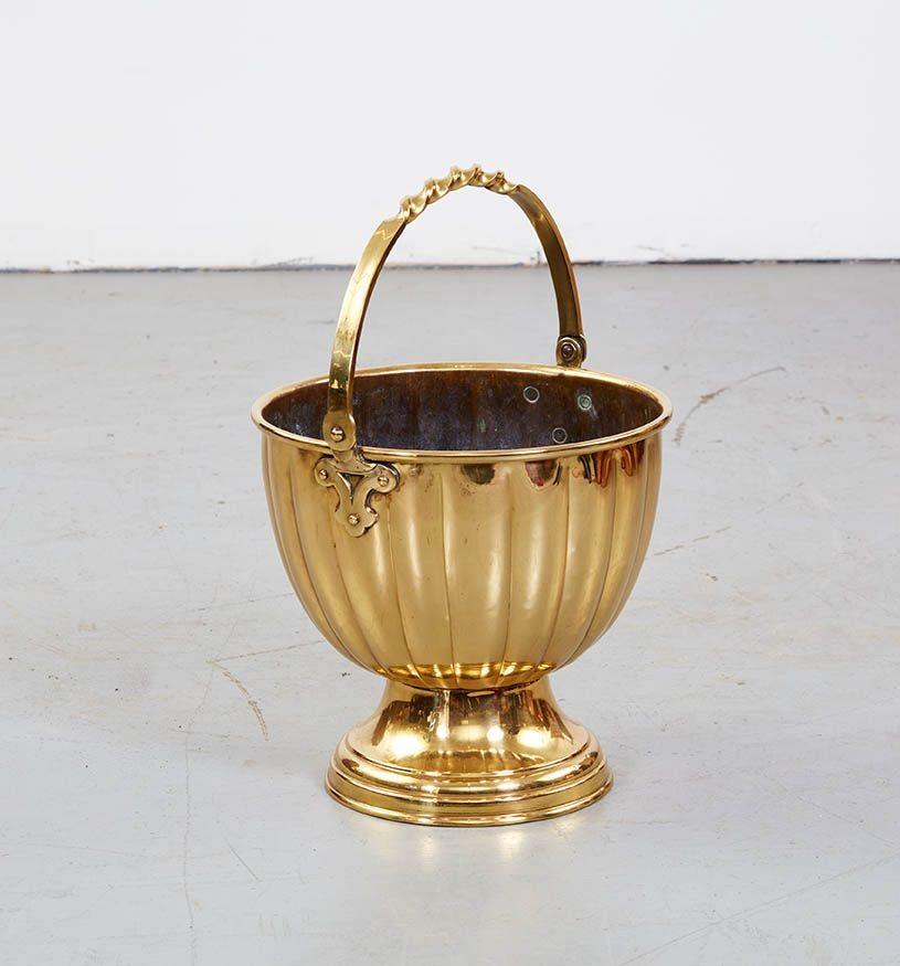 A decorative bucket having substantial fluted bowl over spun foot, with fold-over brass twist carrying handle. Handsome in bright polished heavy brass. Now would make a distinctive and impressive flower, kindling or champagne container.
