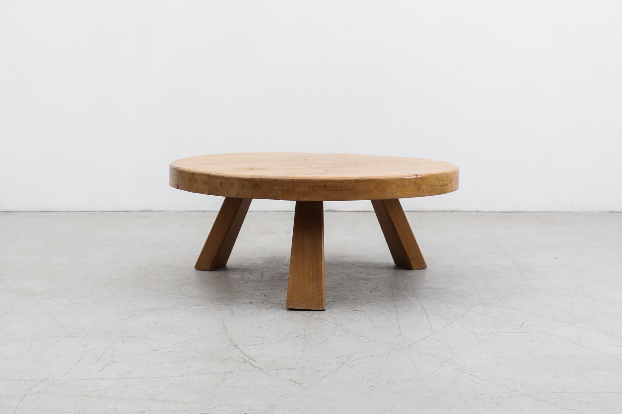 This Brutalist heavy round coffee table is made from solid oak and has three sturdy square legs. It has been lightly refinished. In otherwise original condition with visible wear and patina consistent with its age and use. Other similar tables