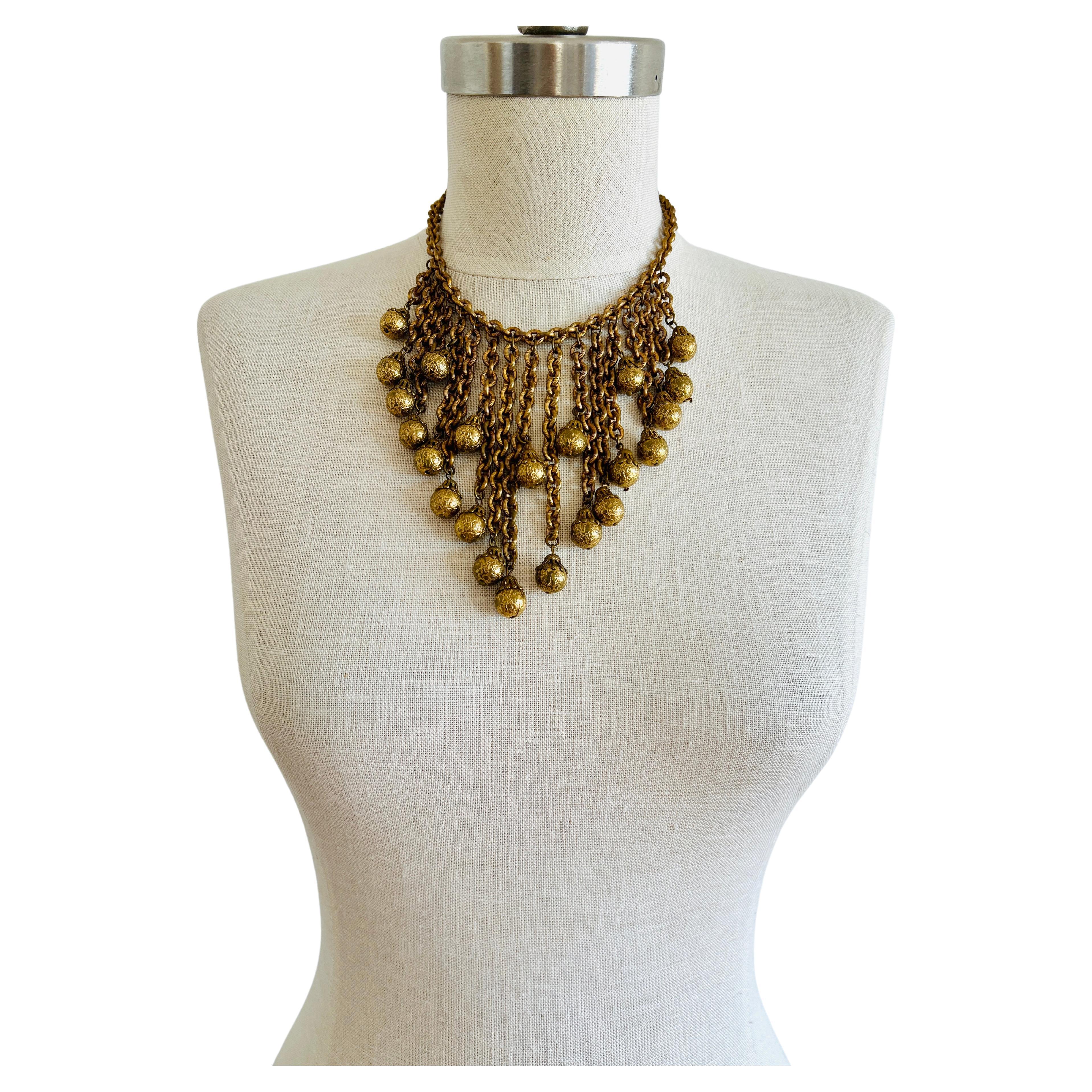 This statement choker necklace is well-constructed, weighing approximately 145 grams. It features 17 varying lengths of RGP chain link tassels with dangling balls. The longest tassel drops over 4