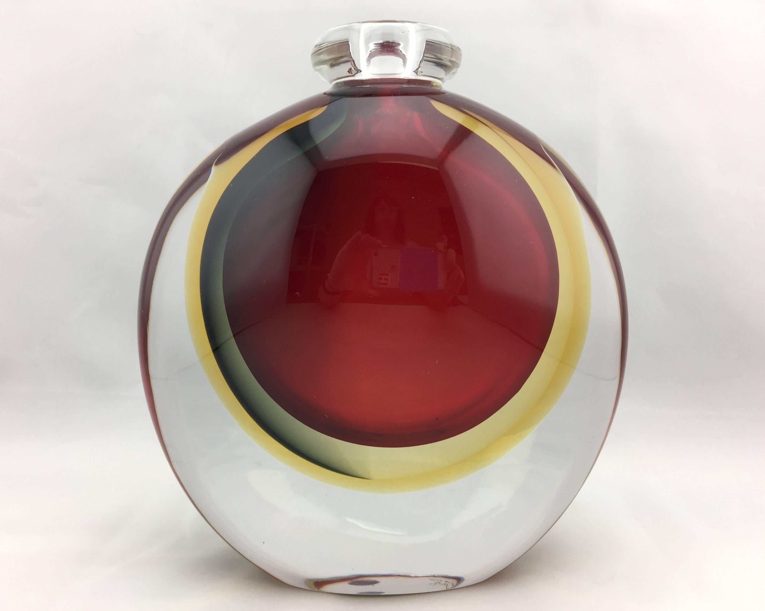 Heavy signed Italian Murano glass vase.
 Clear glass encases red and yellow glass of circular shapes in order to make it seem as if the colors are floating. Very sophisticated and timeless. The vase is Signed and dated. It also still retains the