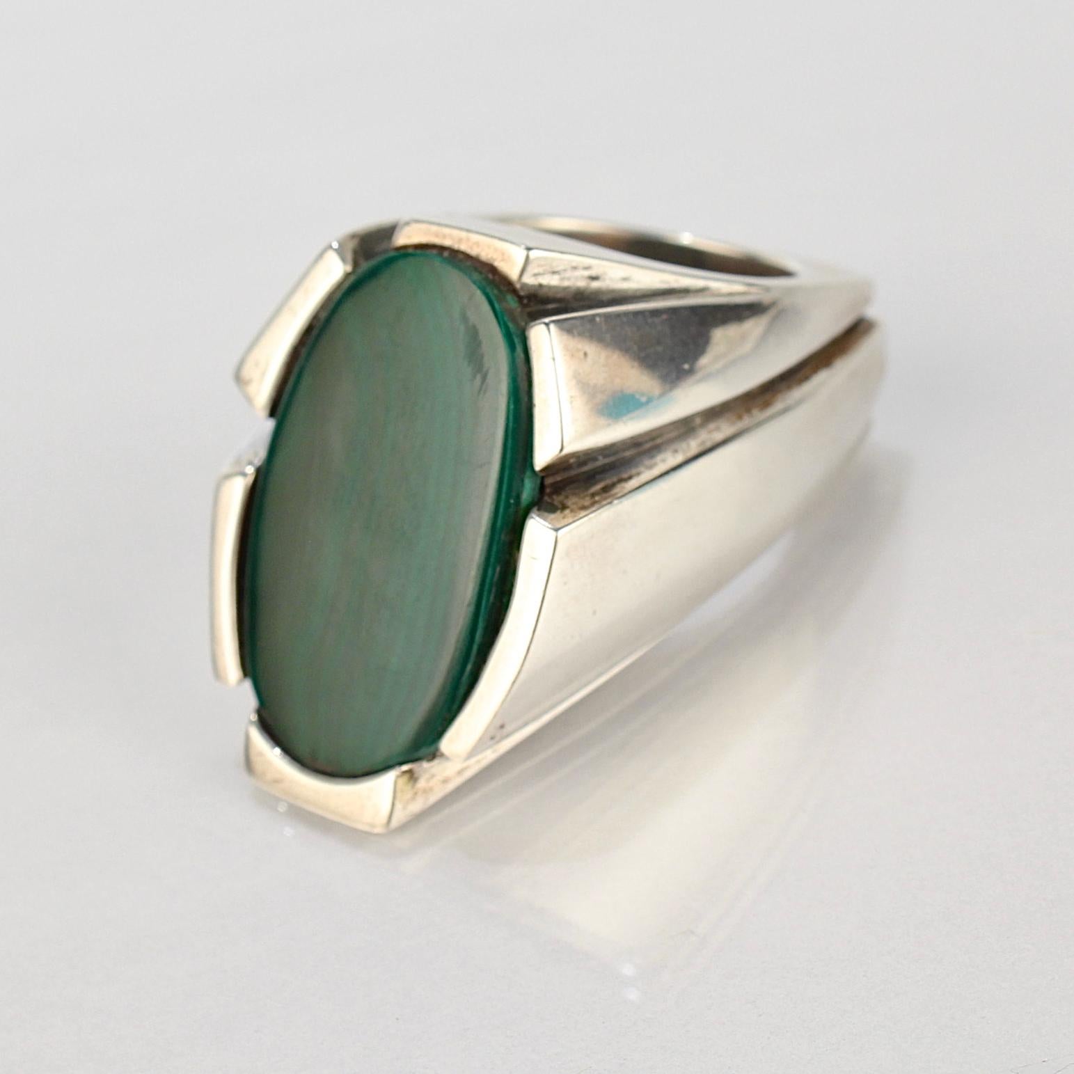 An impressive Wesley Emmons modernist signet ring.

Comprised of sterling silver, this stoutly made ring is set with a flat oval Malachite cabochon. It sits high on the finger and has great weight!

Emmons was an important jewelry maker in
