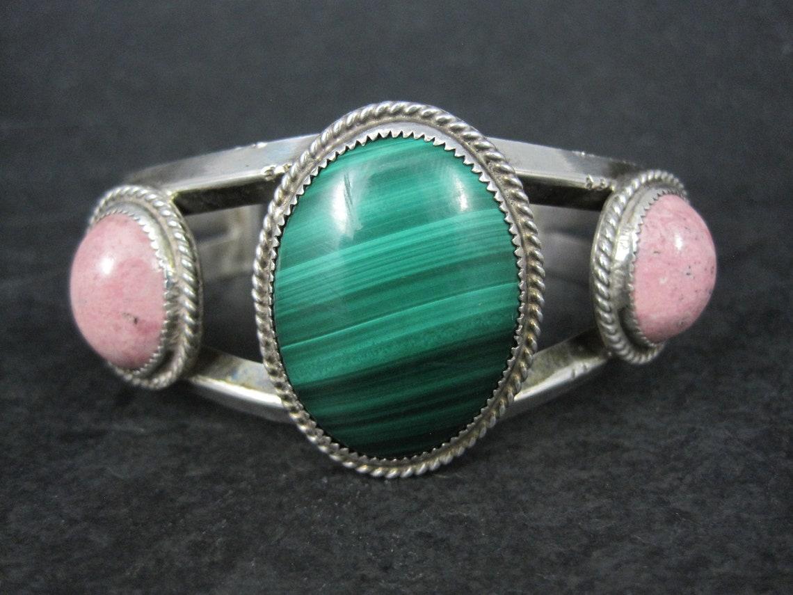 This stunning Southwestern cuff bracelet is sterling silver with malachite and rhodonite gemstones.

The face of this cuff measures 1 5/16 inches and tapers down to 7/16 of an inch.
It has an inner circumference of 6 1/4 inches including the 1 1/4