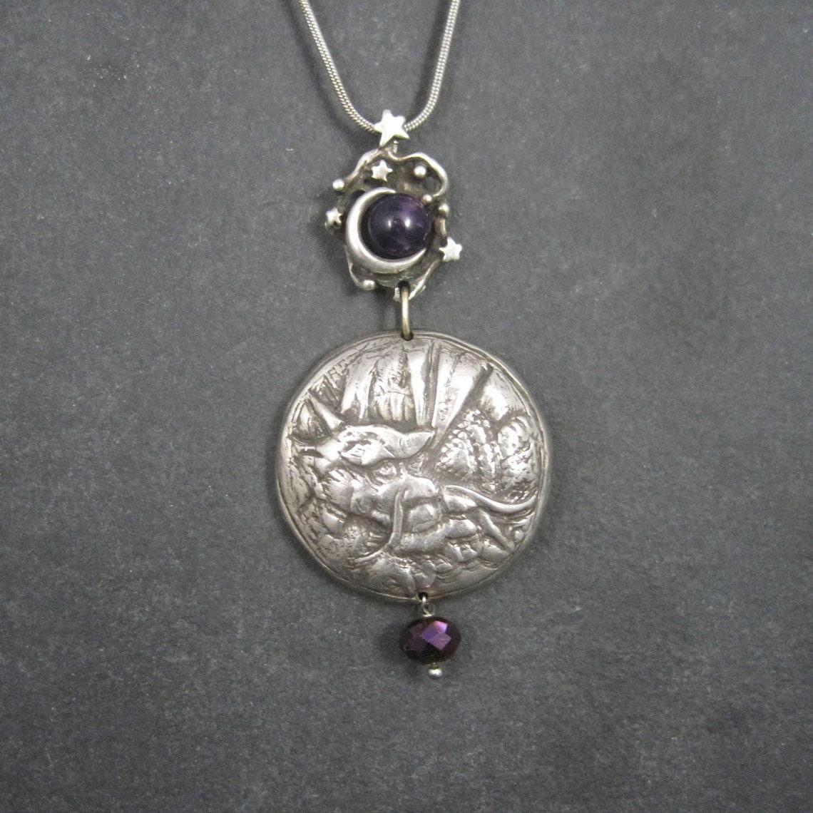 This beautiful sterling silver pendant is one of a kind.

The top features a celestial theme with a crescent moon wrapped around an amethyst sphere.
The second section is connected through a 14k gold loop. It is a heavy Asian style dragon.
The last
