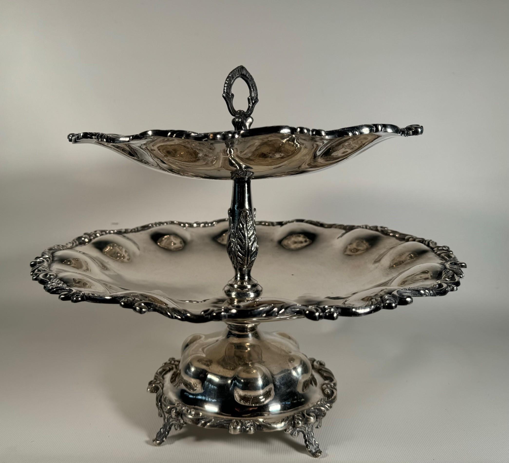 Se trata de una especie de epergne, pero no para flores, sino para fruta o pequeños pasteles. Cada uno de los niveles es abombado y tiene un borde de acanto estilizado y un tallo con asa. Se eleva sobre cuatro patas frondosas. Es una pieza imponente