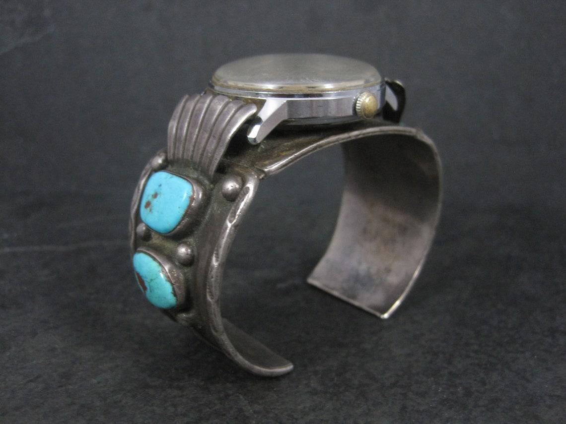 This gorgeous vintage watch cuff is sterling silver with natural turquoise.
It features a basic vintage Timex manual watch that seems to work fine.

The watch cuff measures 1 1/4 inches wide. It has an inner circumference of 6 3/4 inches including