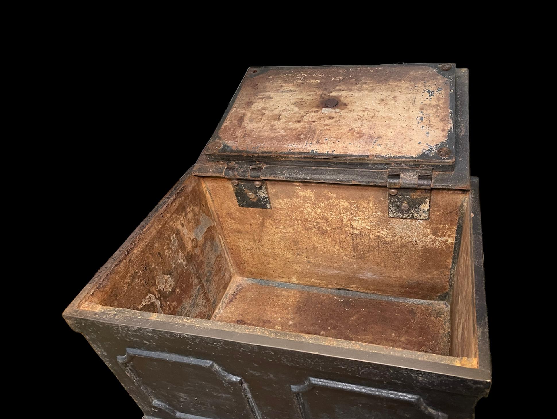 This is a heavy iron storage/safe box. The rectangular metal box is adorned with octagonal shaped repousse molding around its sides. The upper side is a hinged lid that has a metal doorknob to pull it up. There is an escutcheon beside the doorknob