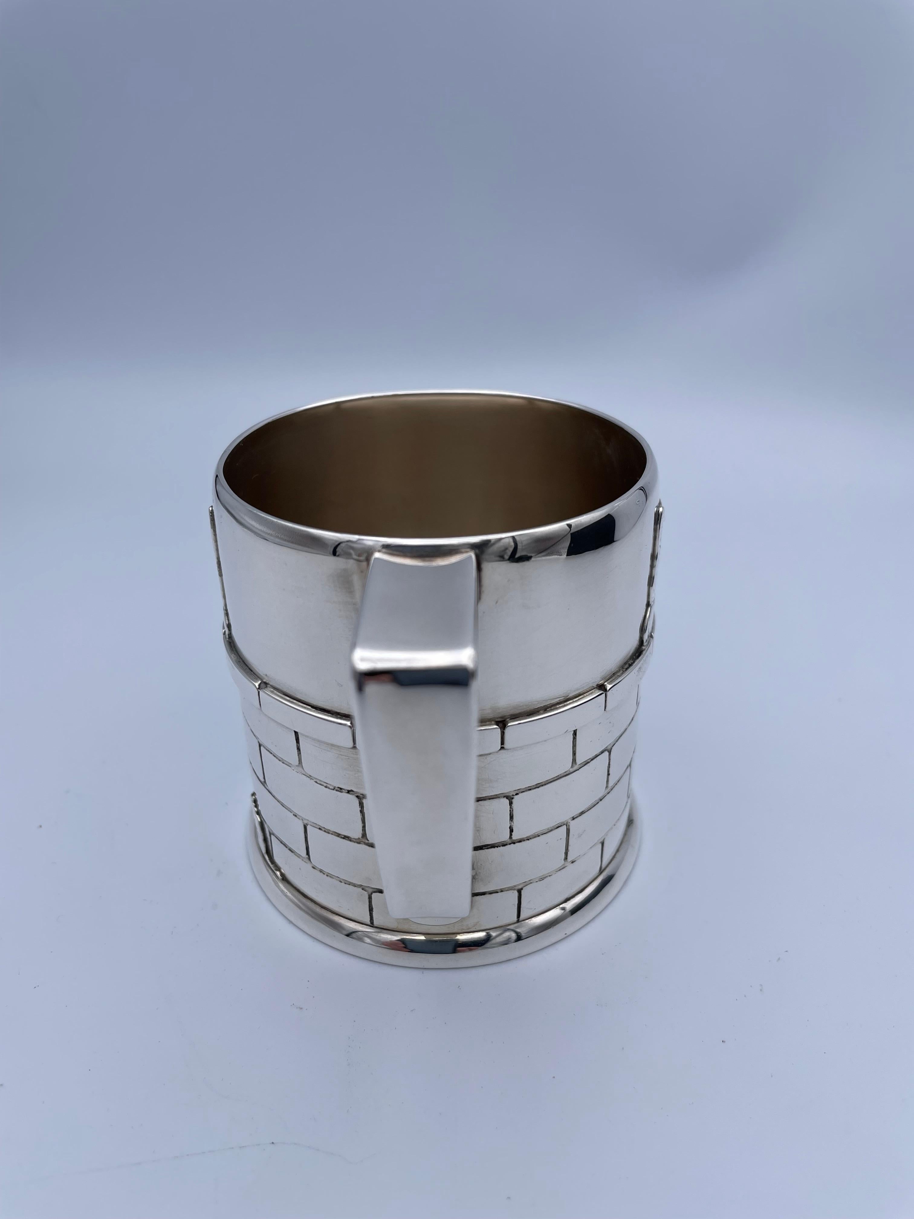 A fabulous baby cup.  Made and signed by TIFFANY & CO.  Unbelievably heavy gauge silver.  Applied detailed decoration of a cat looking over a brick wall at a mouse.  There is an applied cat head on the front and back of the cup.  Large size cup.  3