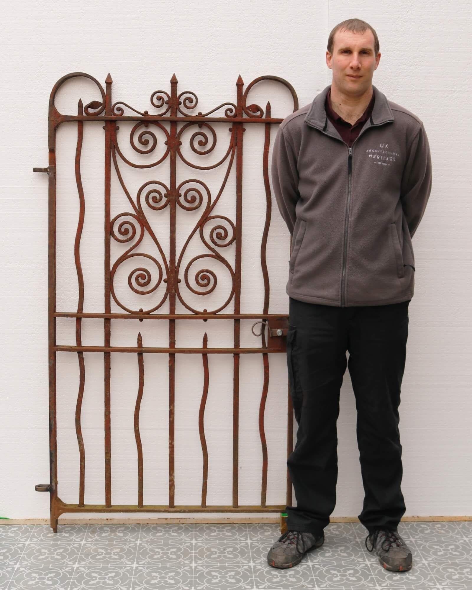 A strong and sturdy Victorian wrought iron pedestrian gate of very heavy construction. Over a century old, it dates from 1900 and features an unusual design of undulating vertical bars around a central framework of ornate scrolls, bringing both
