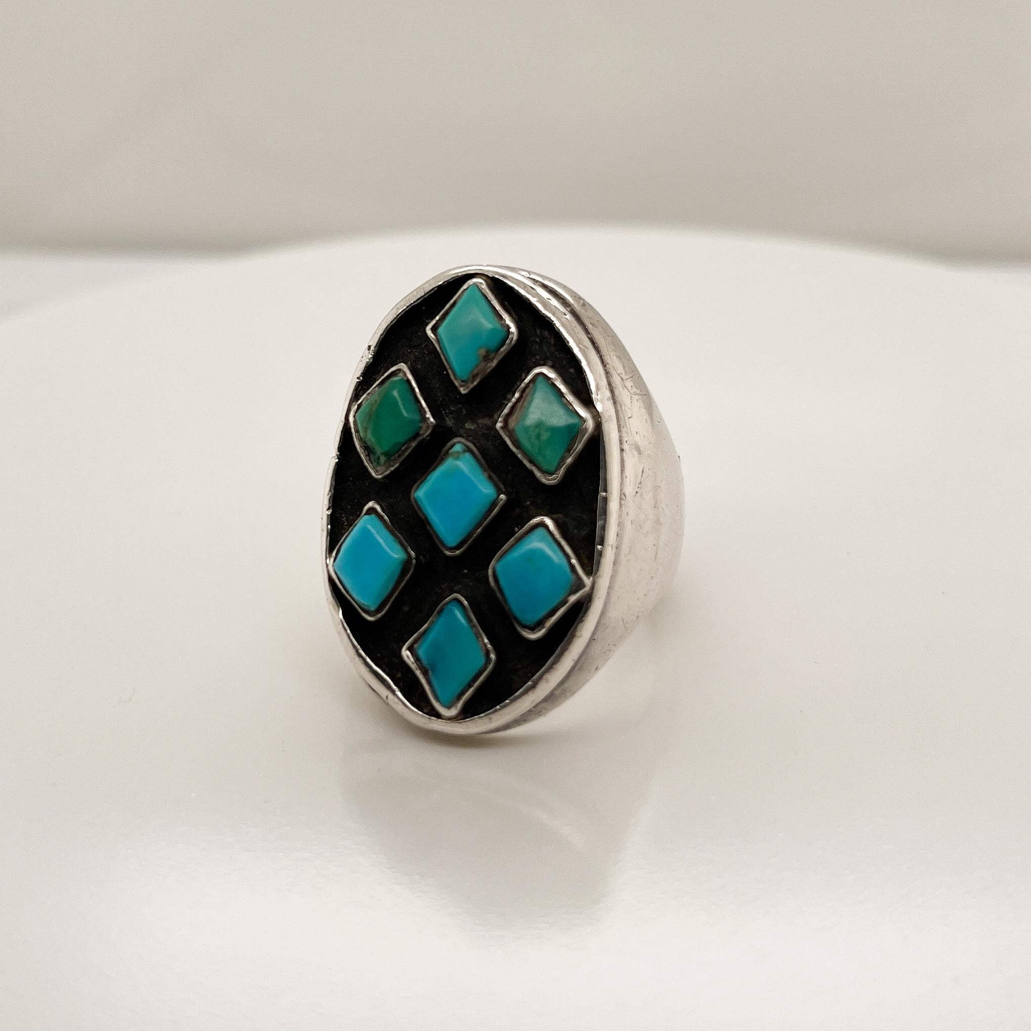 A fine vintage Navajo ring.

Crafted in silver with 7 diamond-shaped bezel set turquoise cabochons that are arranged on a recessed liver sulfur patinated head.

A fine Old Pawn signet style ring!

Date:
20th Century

Overall Condition:
It is in