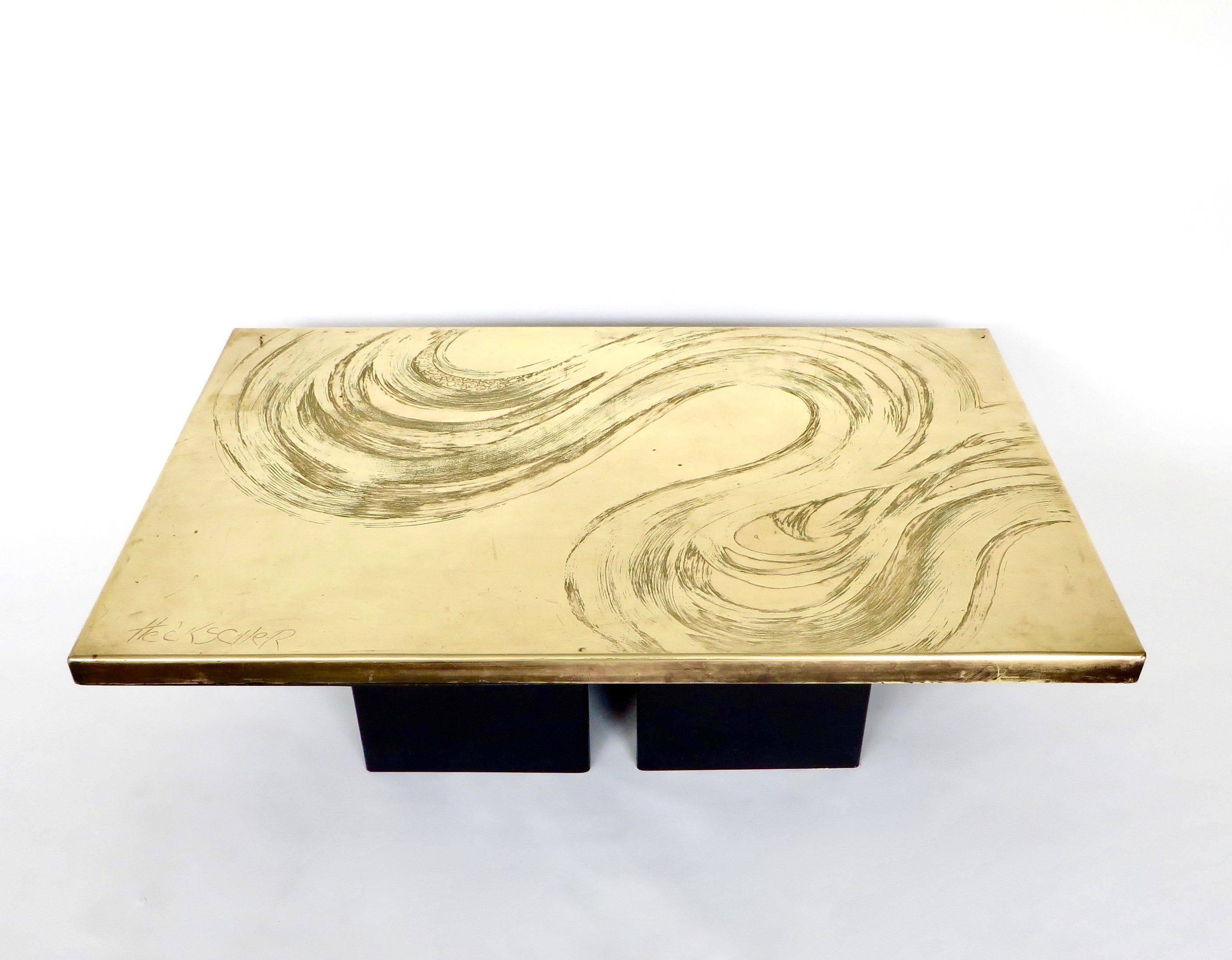 A vintage Belgian etched brass coffee table on two black enameled metal pedestals. The pattern is like a wave or cloud with varying deeply etched lines and drops of patinated brass. Newly polished with age appropriate wear to the surface. The etched