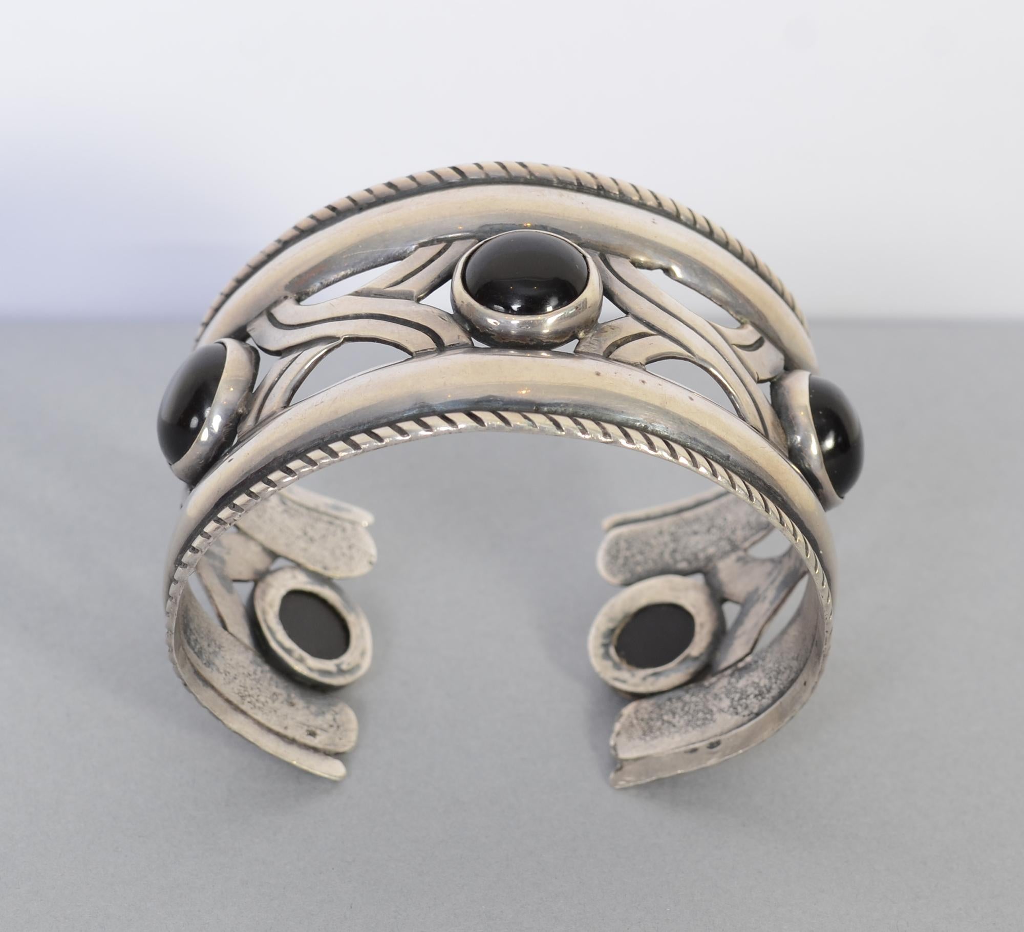 Unusual cuff bracelet by silver master, Hector Aguilar. The bracelet alternates five cabochon onyx stones with stylized silver X's. The X's, as well as the rope banding on top and bottom, are oxidized to carry through the black of the onyx