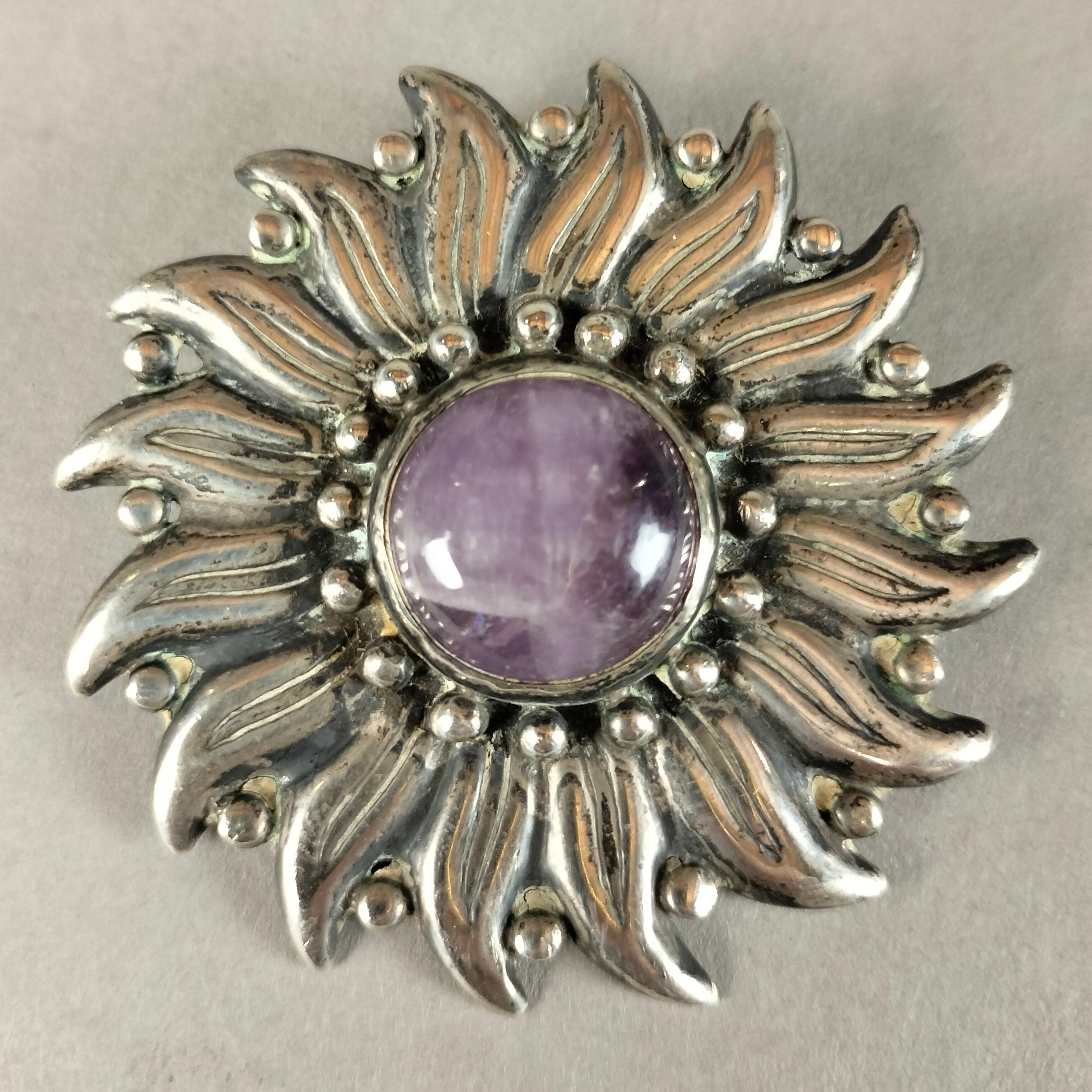 An interesting 1940's Mexican 0.940 Silver brooch by Taxco silver designer Héctor Aguilar. The sunflower-shaped brooch is shows an amethyst quartz in the middle and spheres surrounding both the cabuchon and the leaves. Marked on the back with the HA
