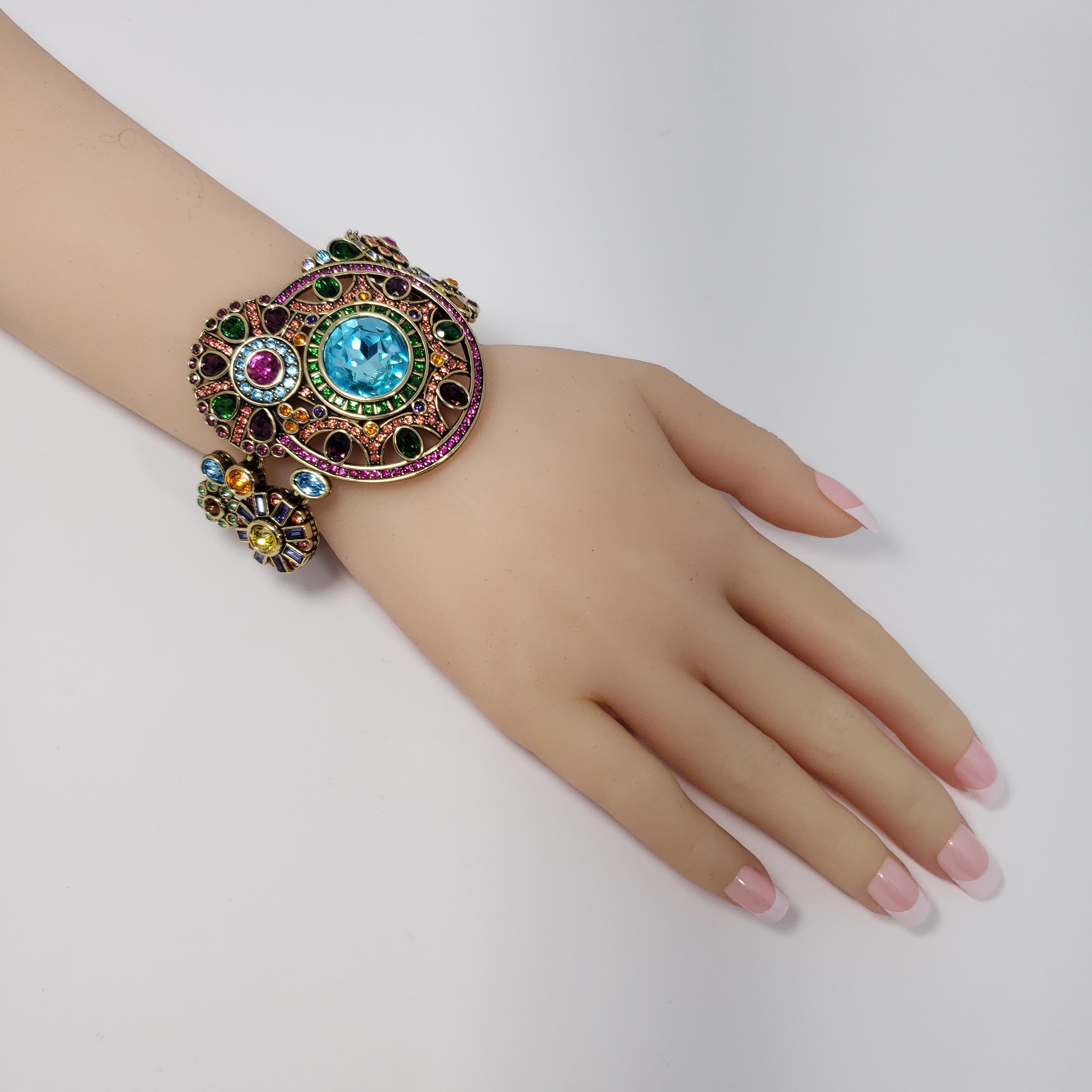 Heidi Daus ornate link toggle clasp bracelet. Features an assortment of round flower motifs decorated with vibrant and colorful crystals. Aquamarine, emerald, amethyst, rose, and other decorative crystal stones bring this mesmerizing bracelet to