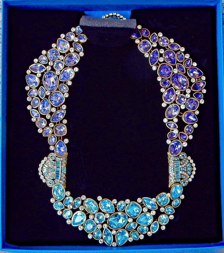 A stunning elevated Heidi Daus crystal collar necklace.  Wide collar necklace features 3 tapered section of bezel-set, multi shaped crystals in clustered patterns.  Three (3) scrolling Art Deco designed stations lined with pave-set round crystals