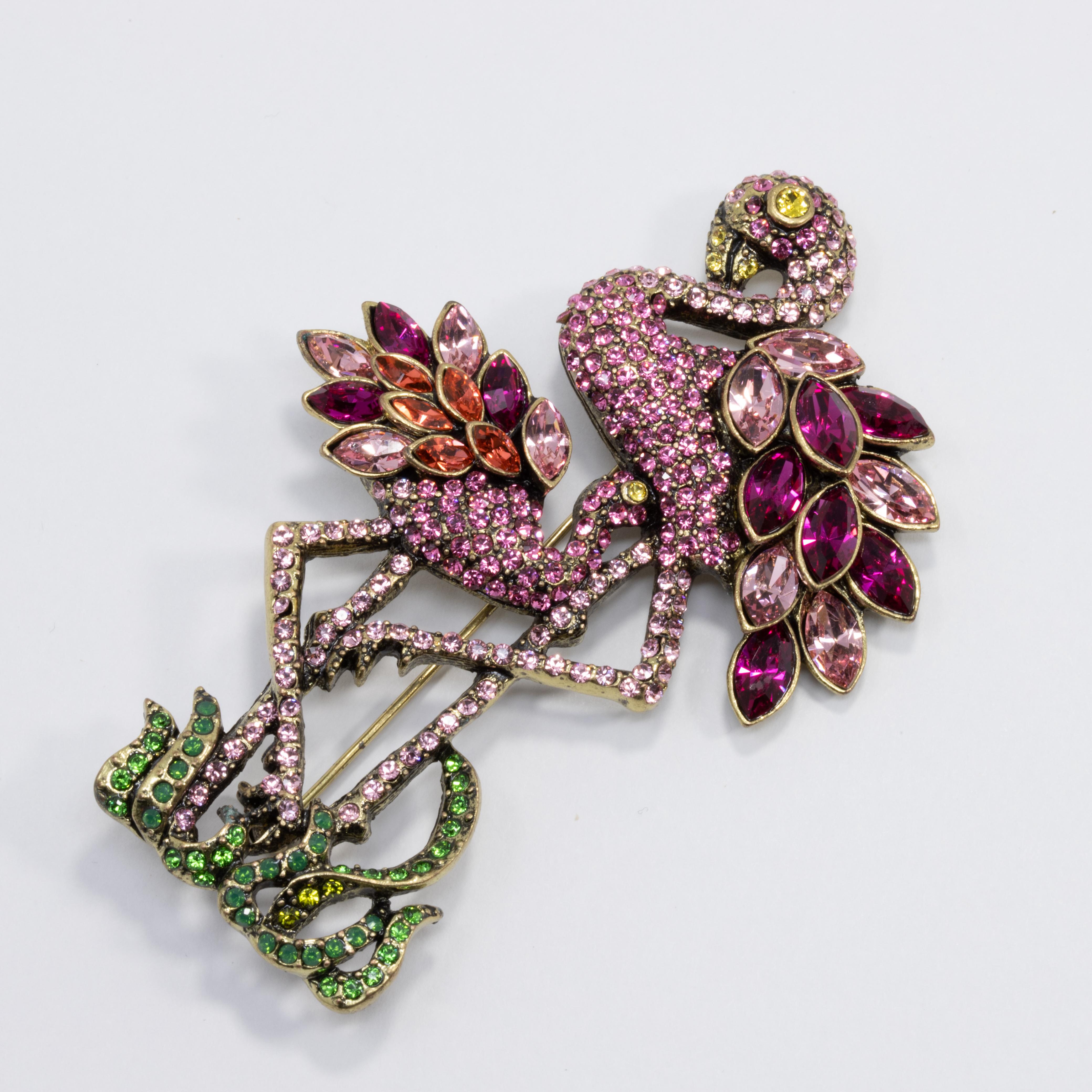 A whimsical pin by Heidi Daus. This lovely brooch features two flamingos, decorated with colorful pave crystals in purple, pink, yellow, and green. Set on matching brass tone metal.

Hallmarks: Heidi Daus, China