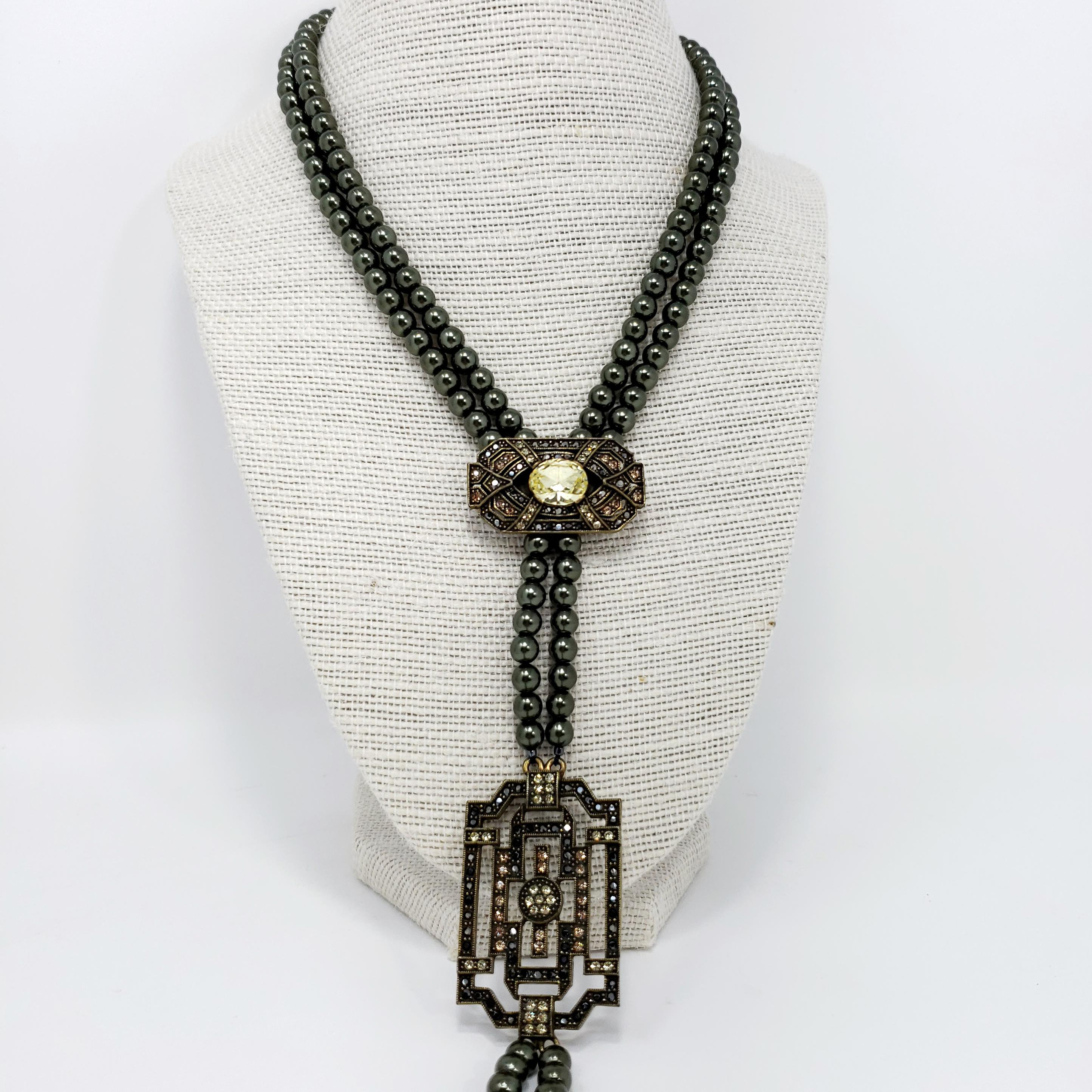 Heidi Daus Lavalier-Anhänger-Halskette mit Art-Deco-Einfluss! Mit zwei Strängen aus falschen Tahiti-Perlen. Geometrische, messingfarbene Akzente, verziert mit Zitronenquarzkristallen, verleihen diesem modernen Accessoire einen stilvollen
