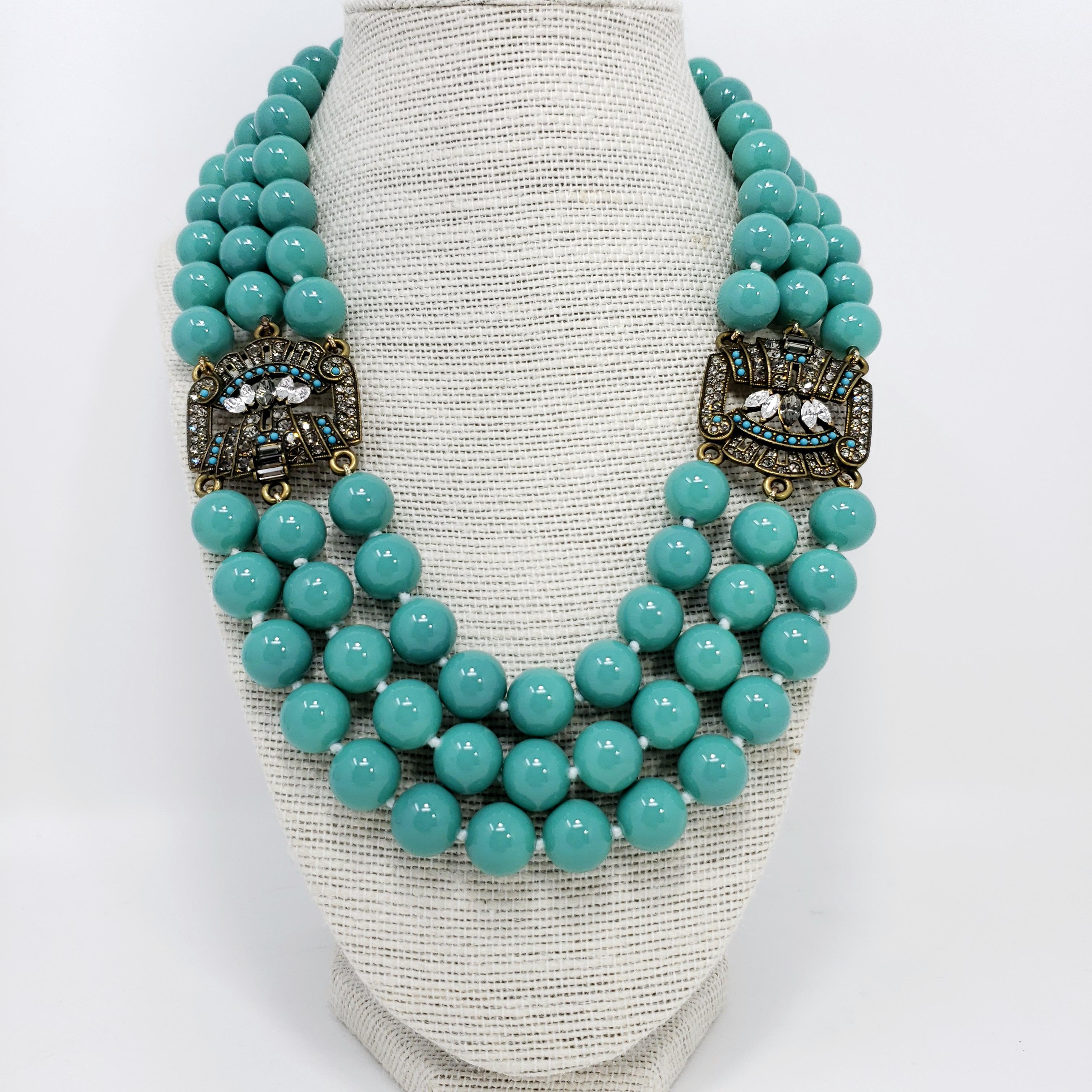 Bold beads by Heidi Daus! Three strands of 12.5mm turquoise beads are connected with antique brass-tone, crystal-encrusted, findings for a sophisticated, yet bold, look.

Length: 47.5 cm

Hallmarks: Heidi Daus, China