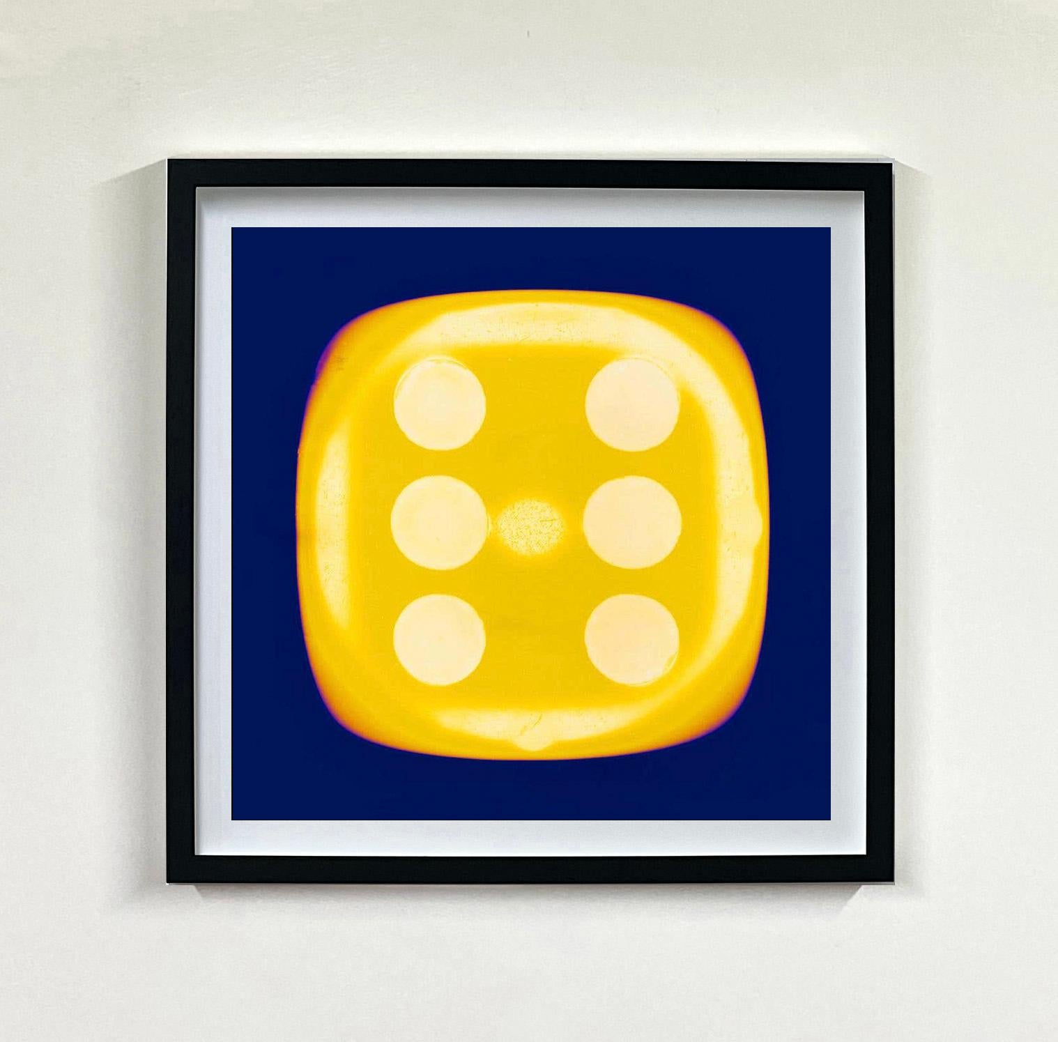 A yellow dice suspended on an inky blue background, hypnotically curious in both content and technique, viewers find themselves pleasantly puzzled. Heidler & Heeps have developed their own dichromatic technique resulting in something, which is