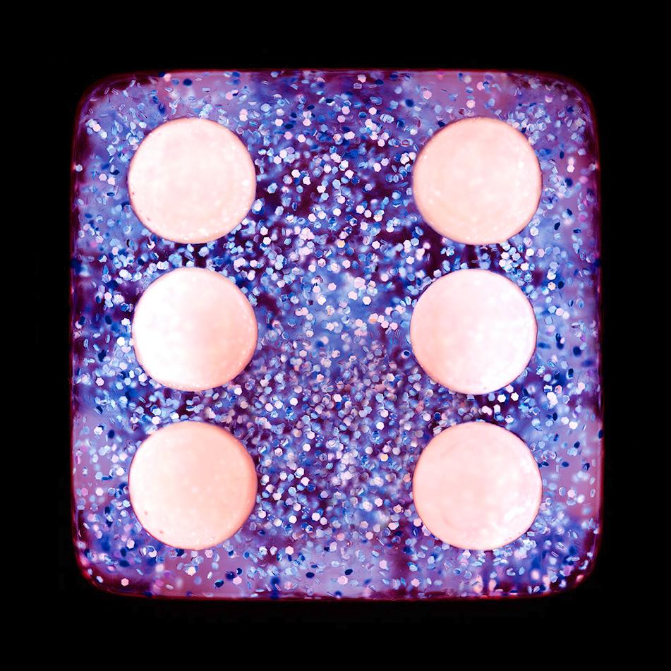A purple sparkly dice suspended on a black background, hypnotically curious in both content and technique, viewers find themselves pleasantly puzzled. Heidler & Heeps have developed their own dichromatic technique resulting in something, which is